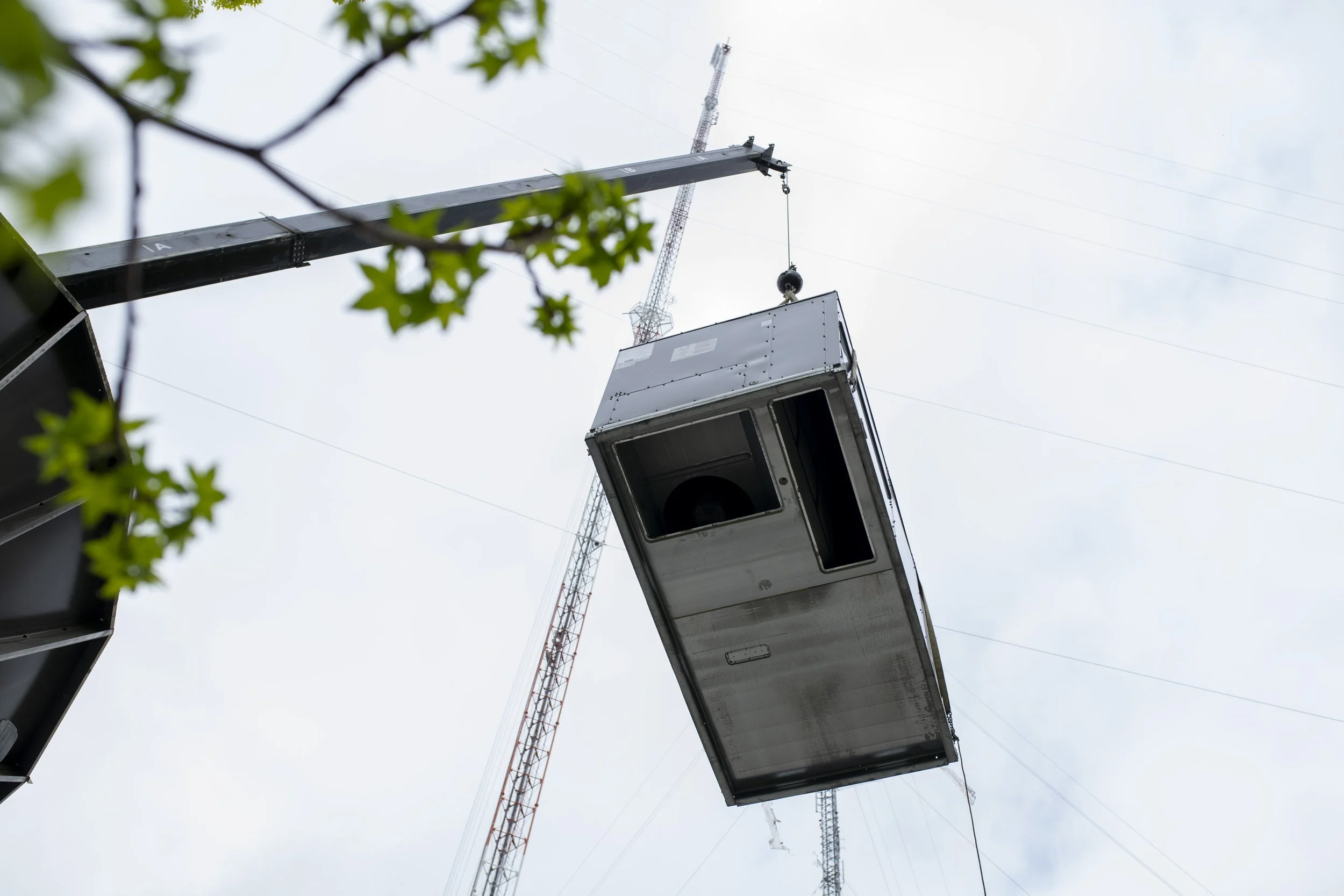 A crane lifting a large, installing HVAC unit.