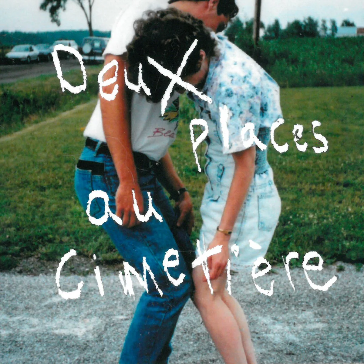 Two people, a young man and a young woman, standing outdoors on a grassy area, sharing an intimate moment with their foreheads touching. The scene appears candid, with a background of parked cars and greenery. White text overlay reads 'dayx all places Queenierre'.