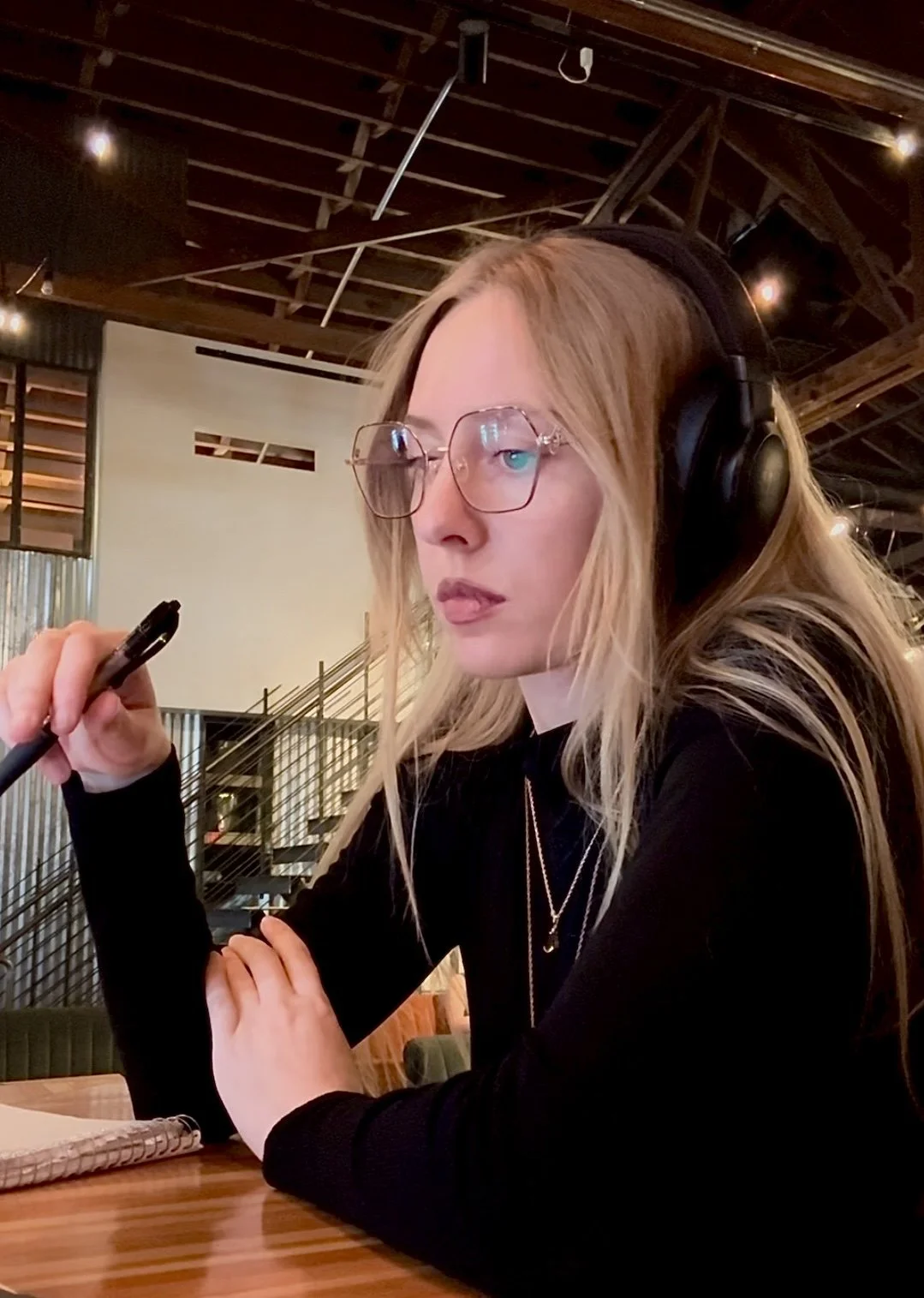 A young video editor, wearing headphones, focusing on strategy for video editing and viral content for her clients.