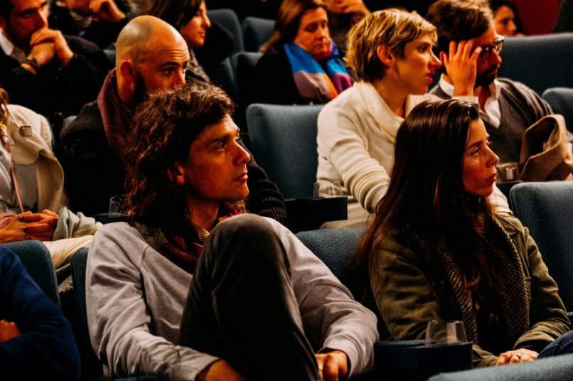 Audience seated in a dark theater watching a presentation.