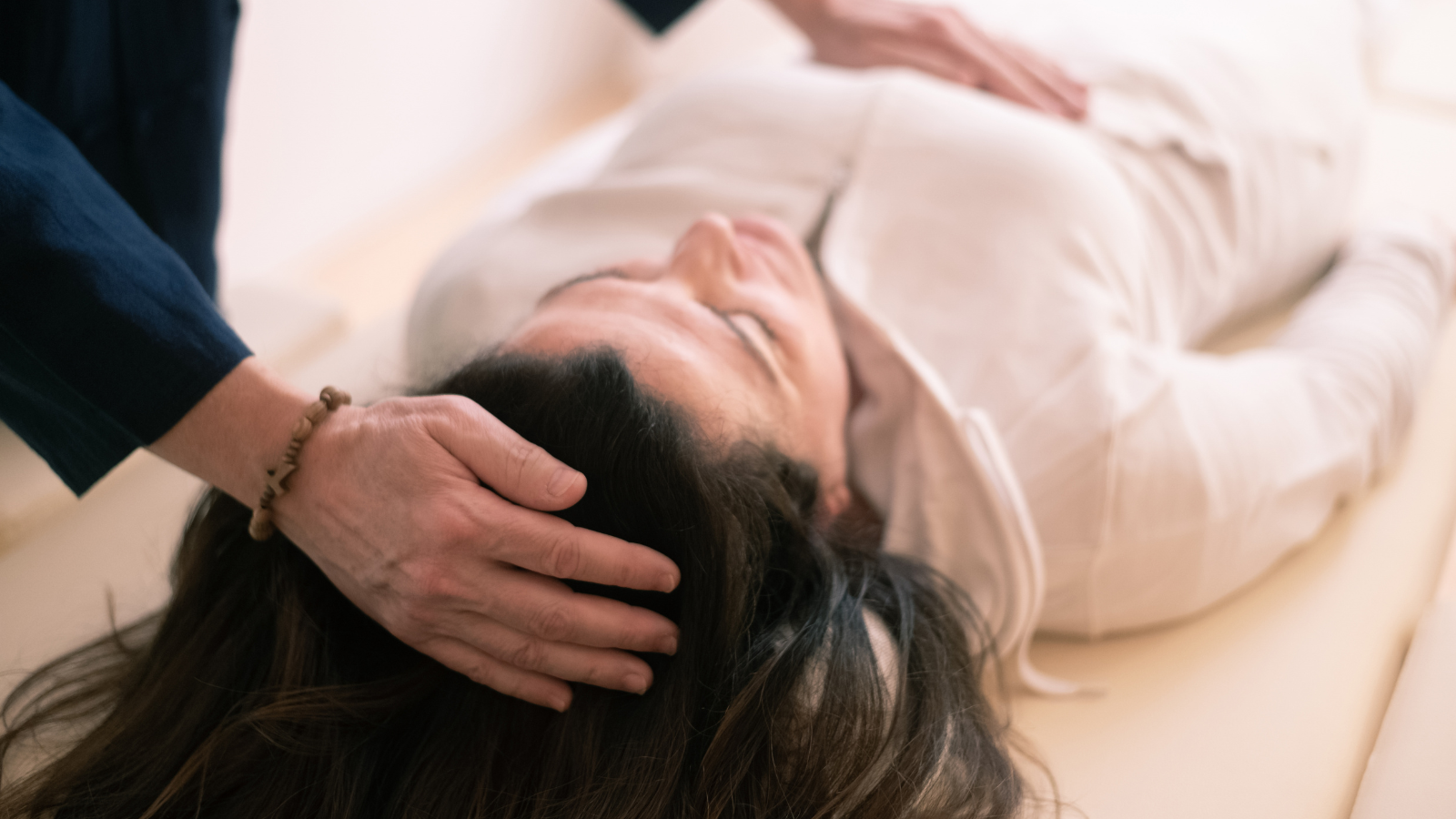 Person receiving a head massage from a practitioner in a peaceful, indoor setting.