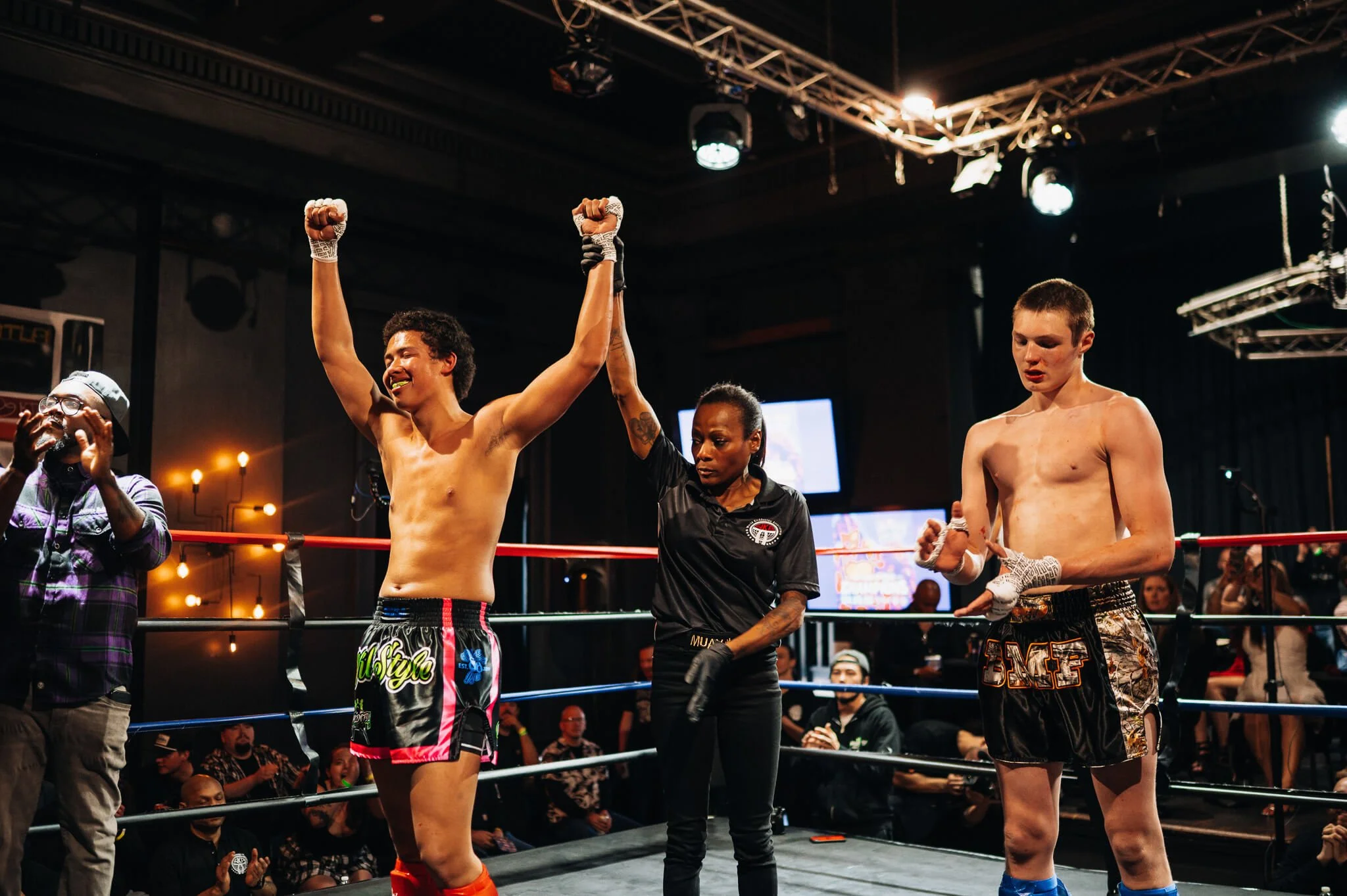 A fighter celebrates victory as the referee raises their hand during an All City Fight Night event.A fighter celebrates victory as the referee raises their hand during an All City Fight Night event.