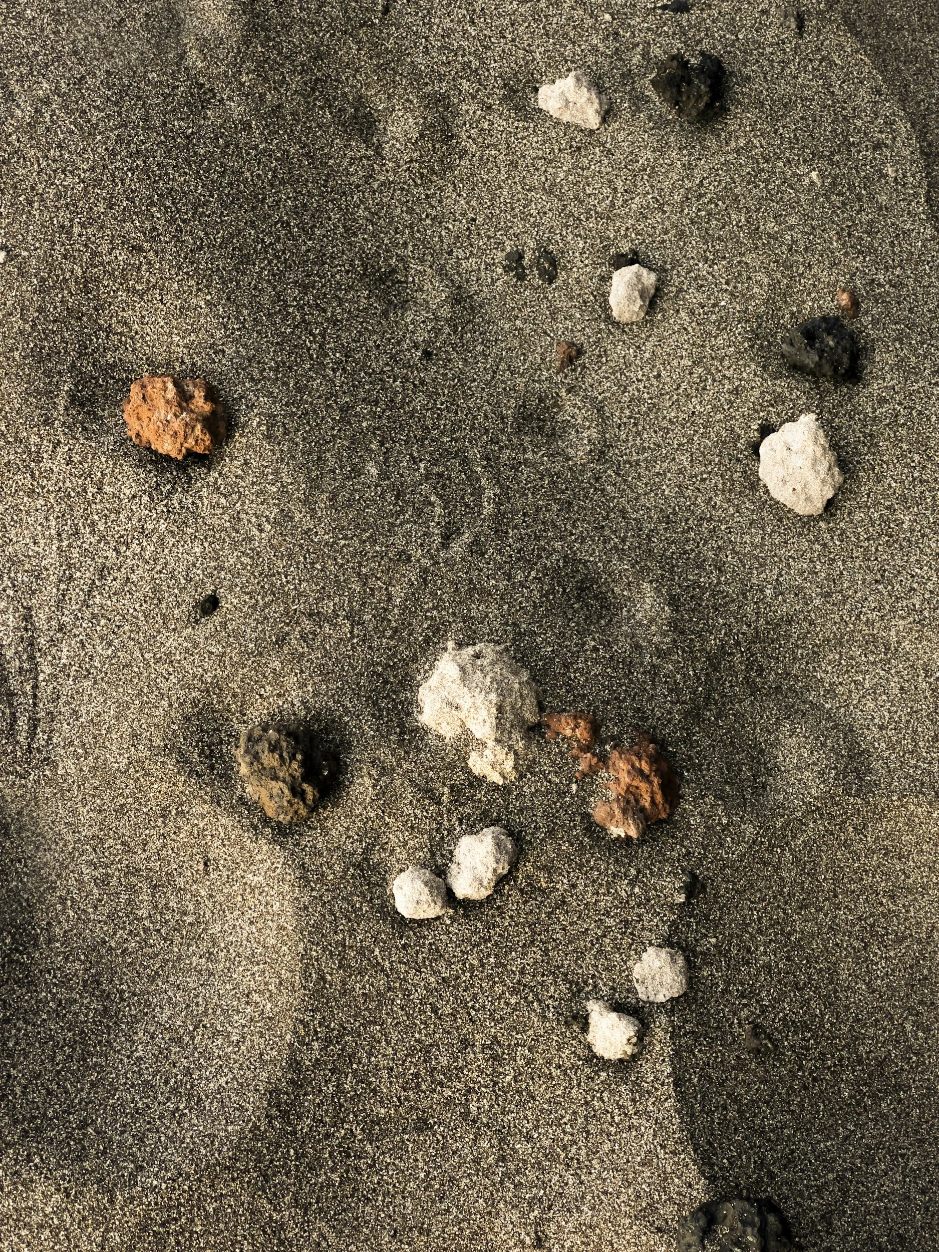 Sand mit verschiedenen kleinen Steinen und Perlen