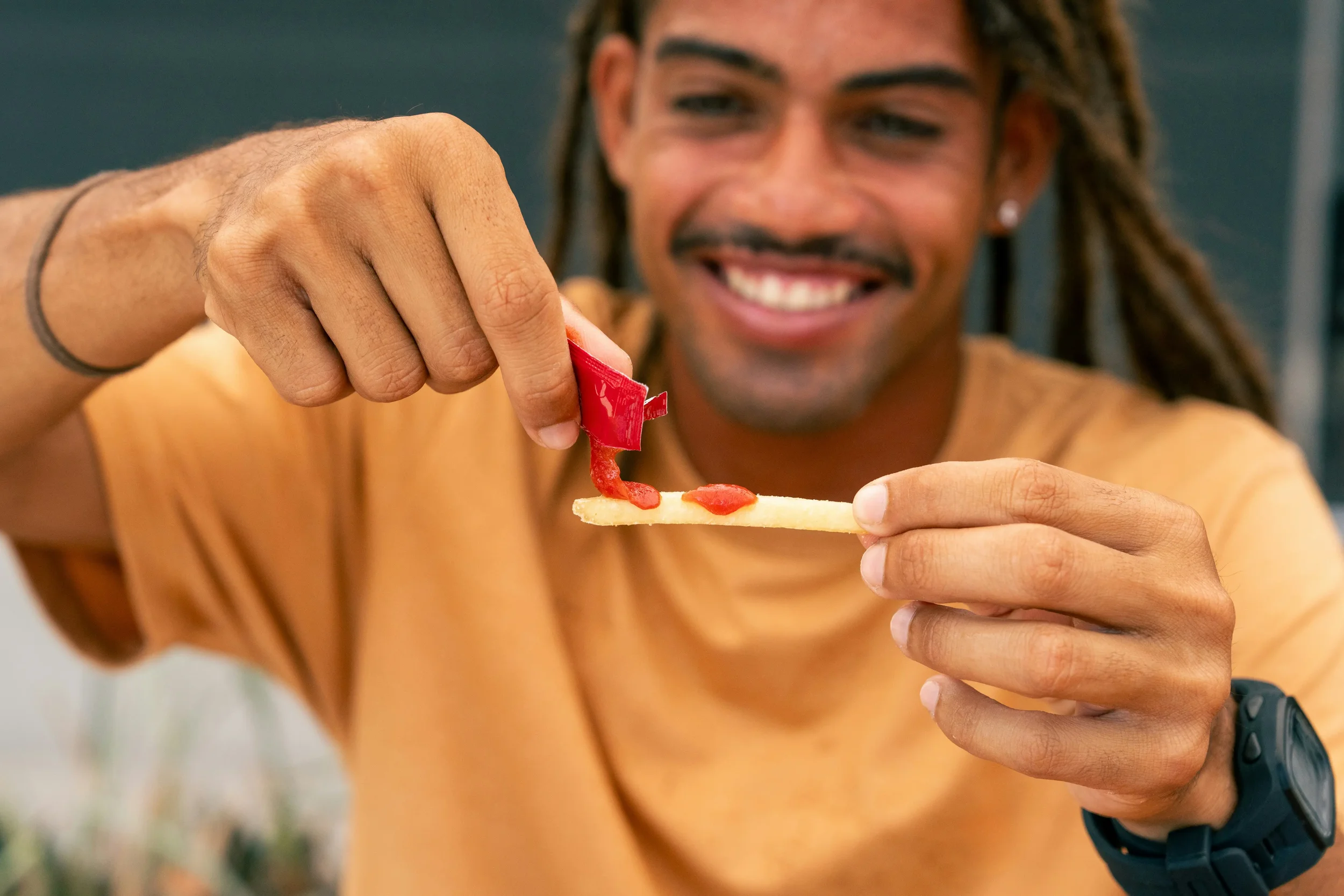 dark skinned man putting tomato sauce onto a single chip
