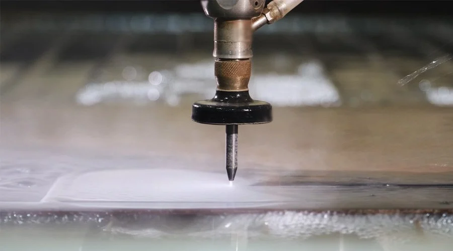 Close-up of a CNC water jet cutting into a metallic sheet, creating a gasket.