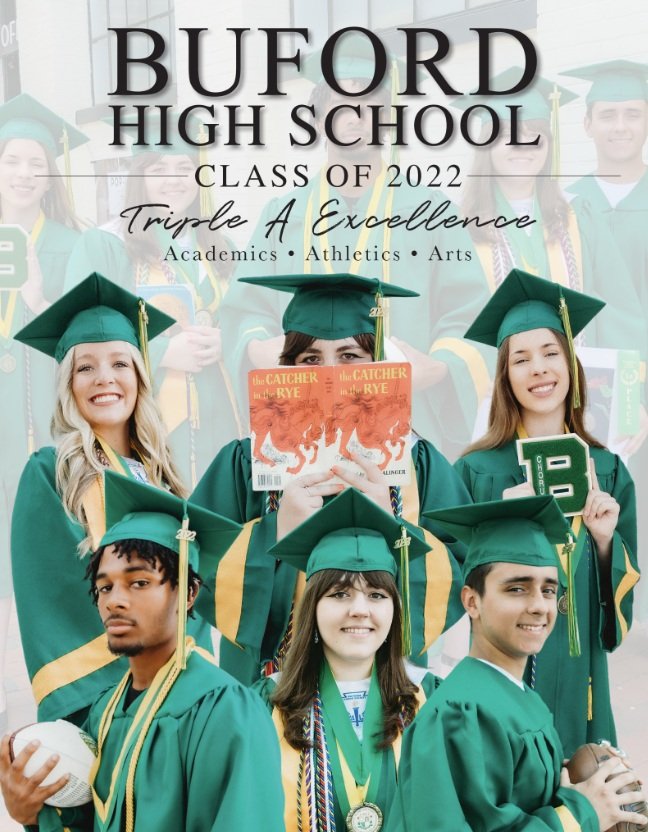 Group of high school graduates in green caps and gowns holding diplomas, medals, and a baseball, with a school banner in the background.