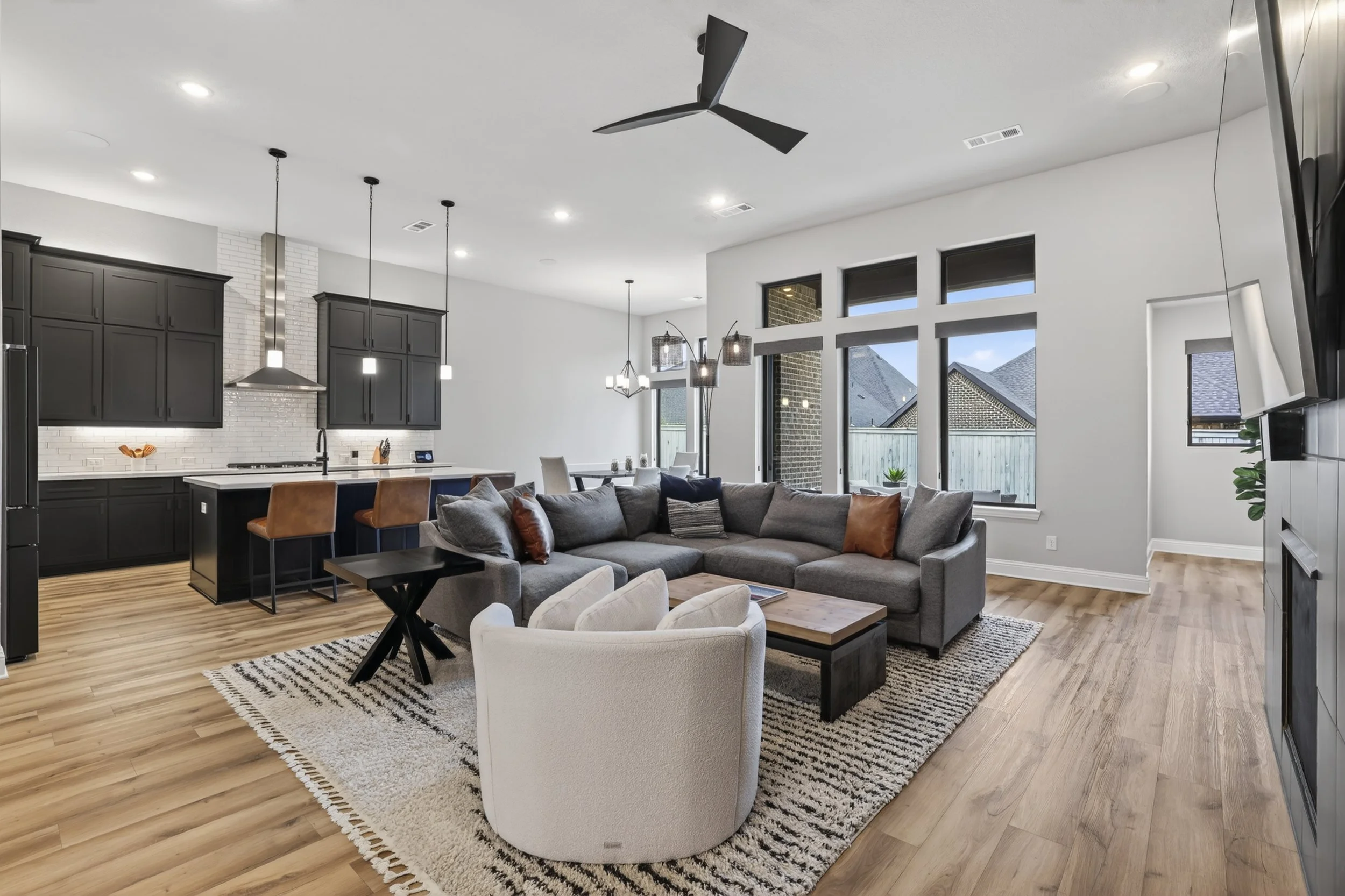 High-end interior real estate photography of a modern open-concept living room and kitchen for a listing in Plano, TX by LuxeAngle Media.