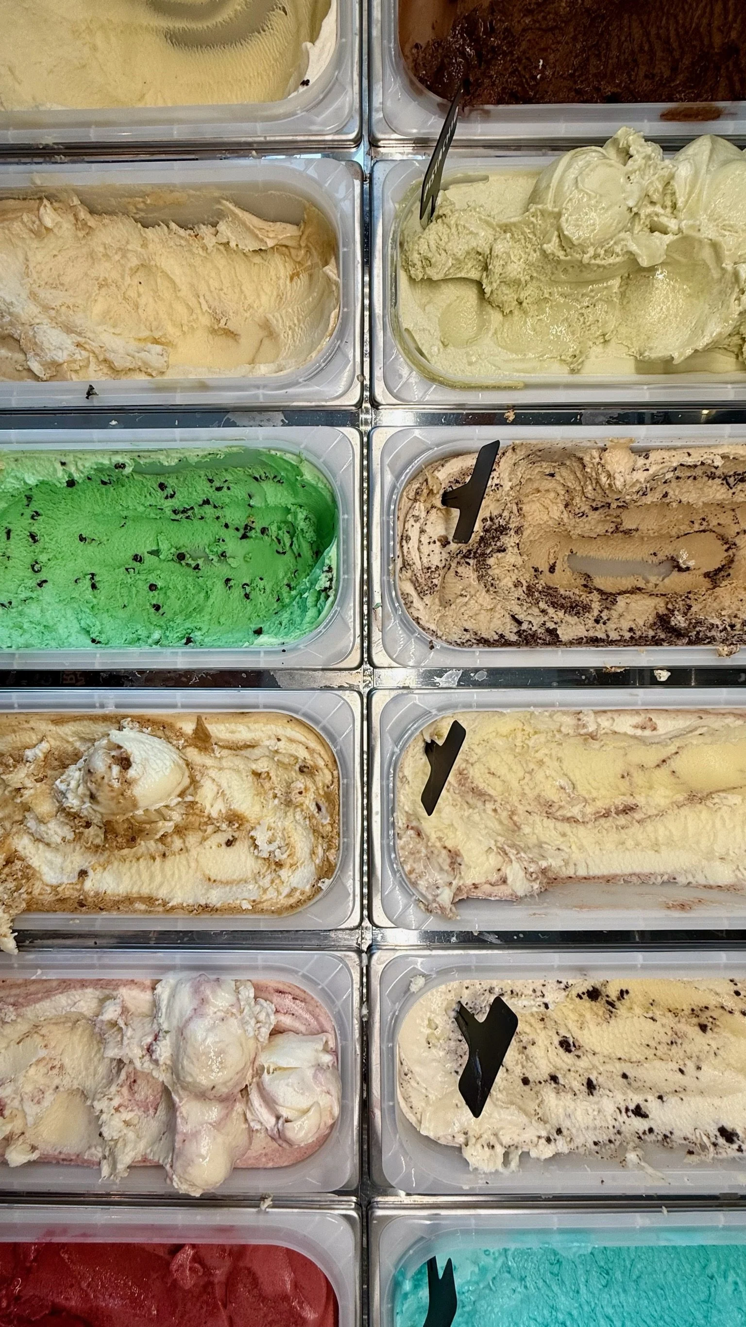 Multiple containers of different flavors of ice cream in a freezer, including vanilla, chocolate, mint chocolate chip, and cookie dough.