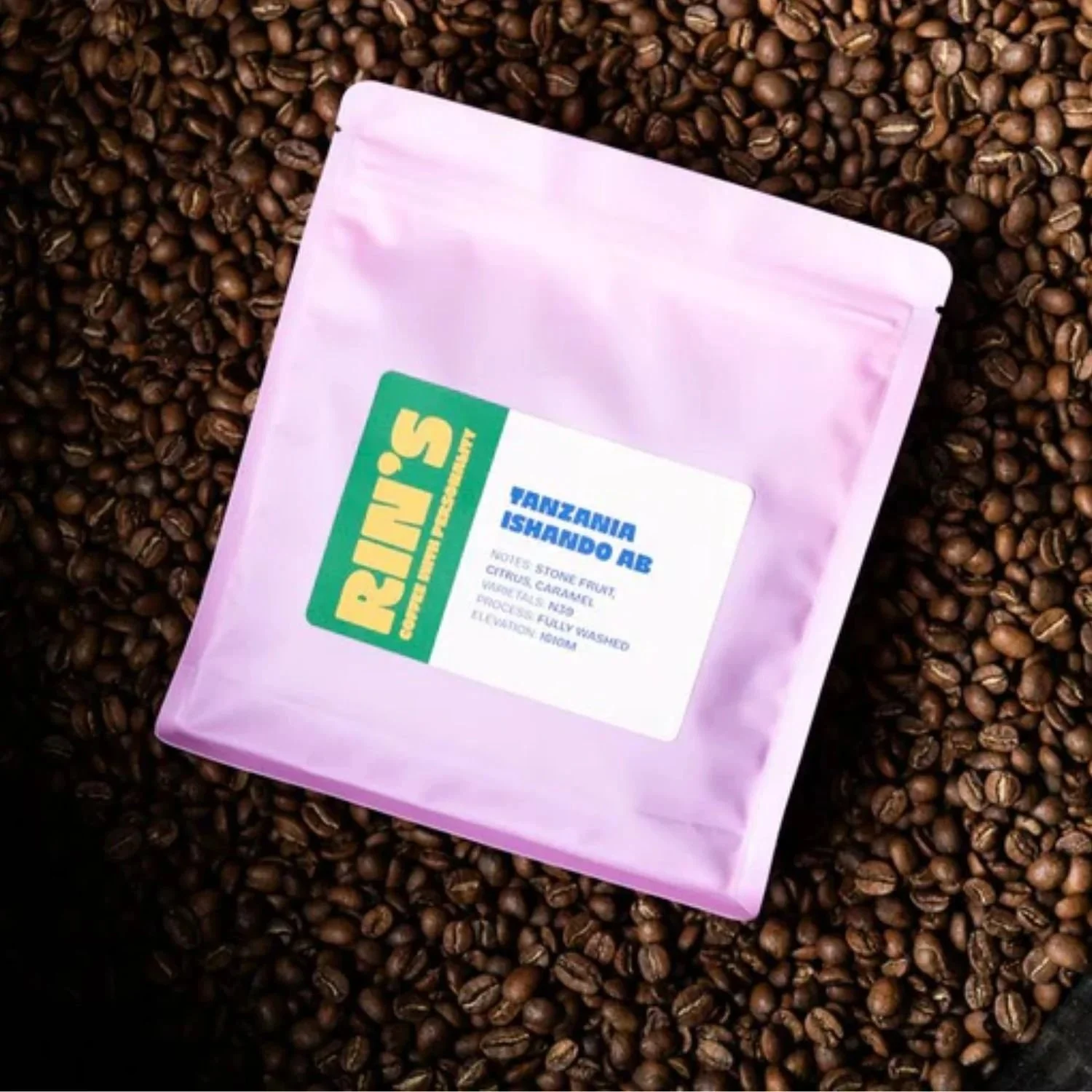 Packet of ground coffee placed on coffee beans