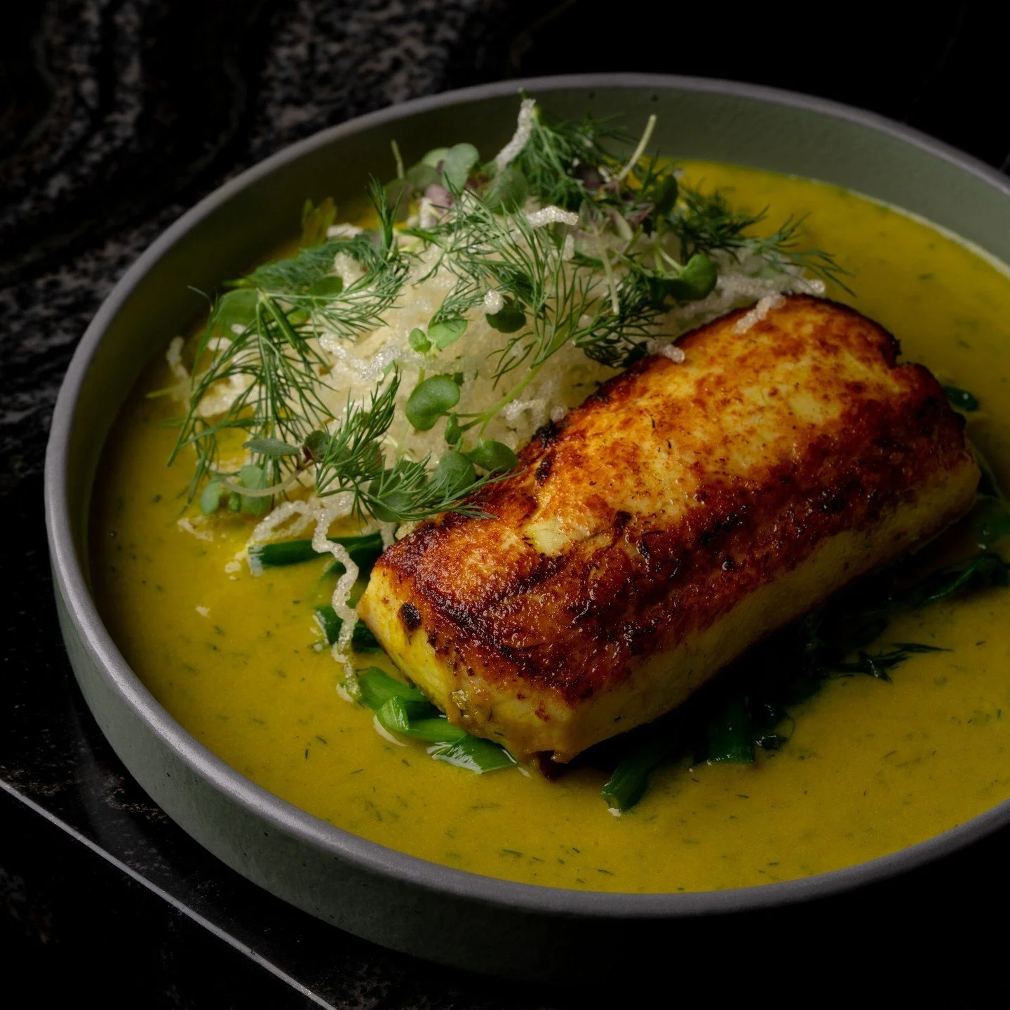 Chả C&aacute; is a popular fish dish native to Hanoi, Vietnam. Our version features seabass marinated in turmeric, garlic, dill, and fish sauce, finished in a beurre mont&eacute;. Served over crispy glass noodles with spring onion.