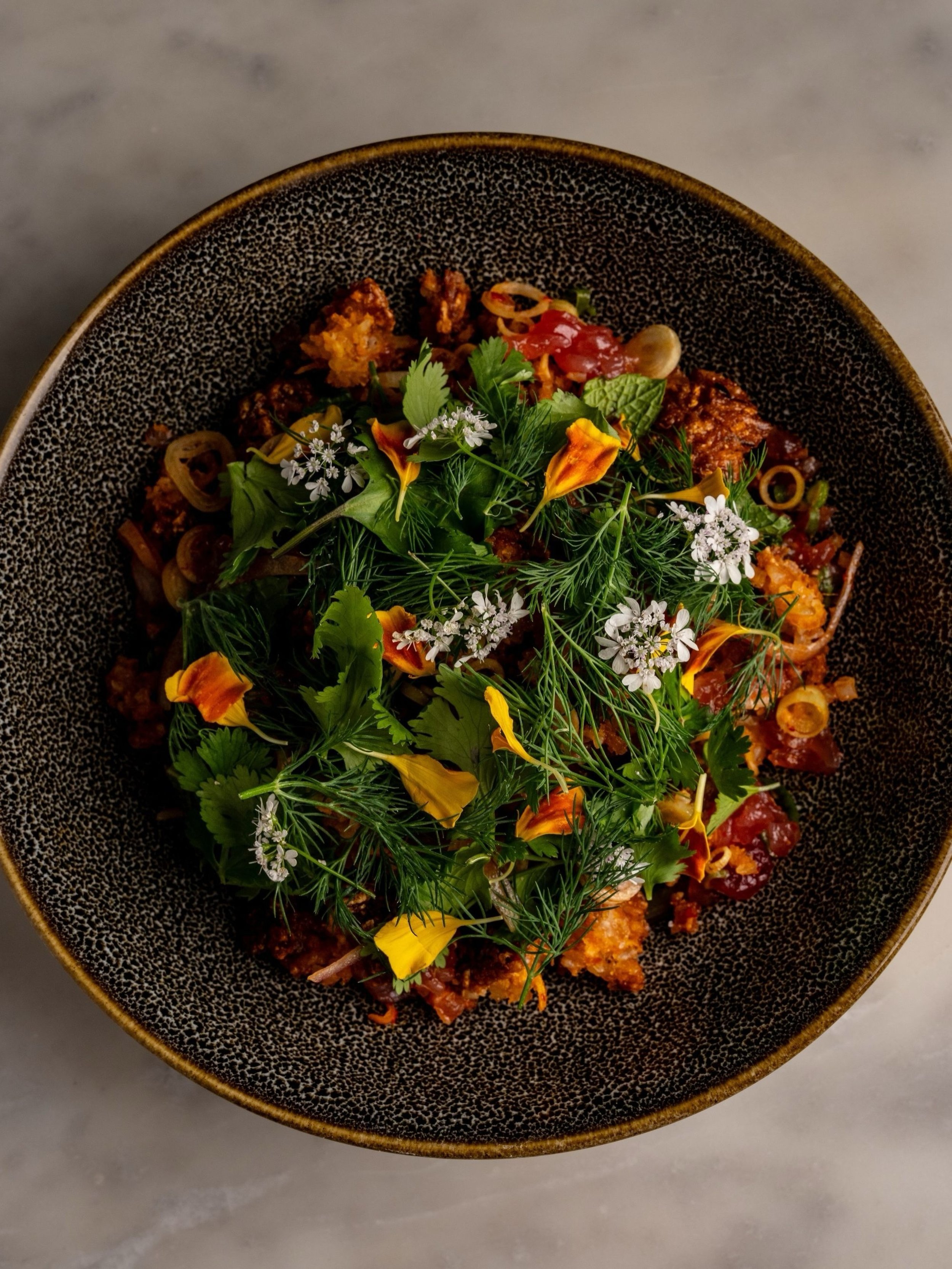 Our Tuna Nam Khao takes its cues from the traditional Lao salad, pairing crispy coconut curry rice with tuna, chili vinaigrette, and fresh herbs. Give it all a good mix before your first bite to bring every component together.