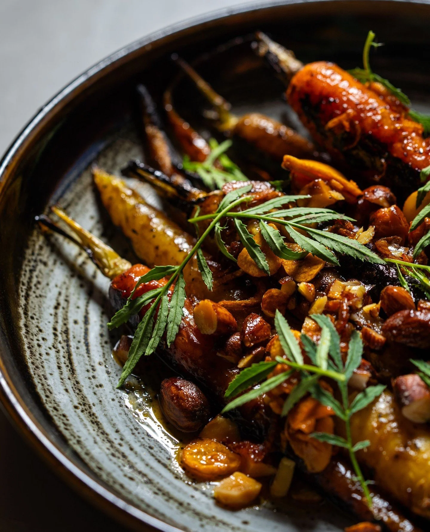 Carrots charred over open coals and glazed with maple black garlic, balancing smoky depth with sweet umami richness. Finished with smoked almonds and crispy garlic-shallot oil for crunch.
