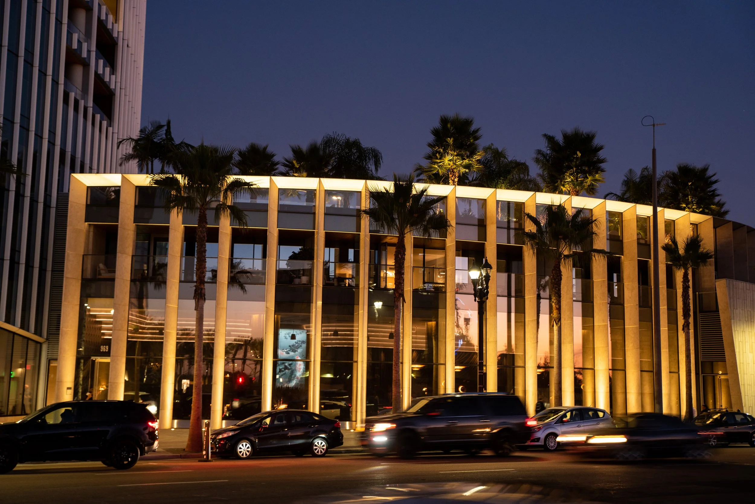 Exterior of Animae restaurant at 969 Pacific Hwy, downtown San Diego at night, with illuminated columns, palm trees, and floor-to-ceiling windows