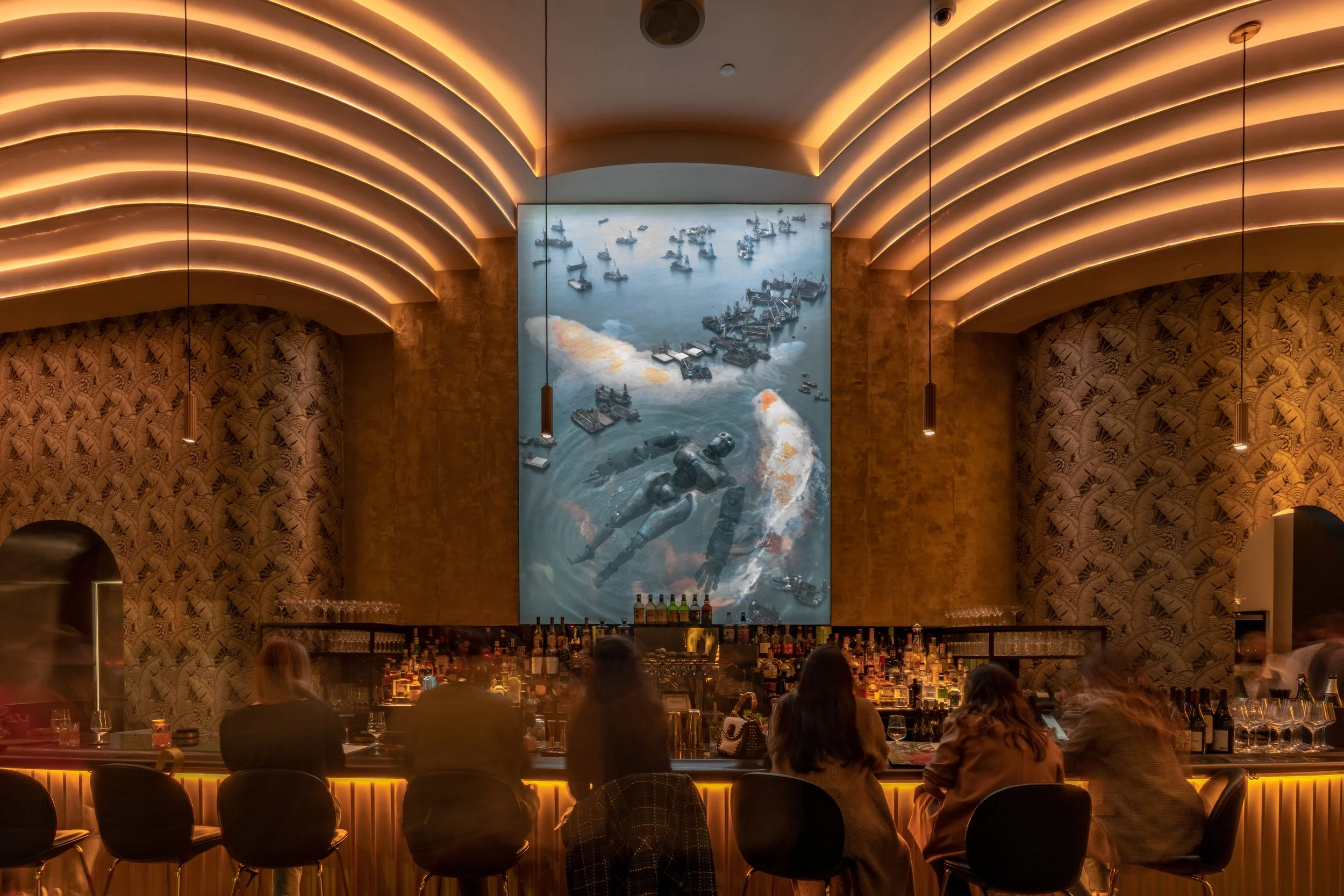 Animae bar at night featuring a large Iron Giant inspired mural, wave-form ceiling lighting, and guests seated along the bar, downtown San Diego