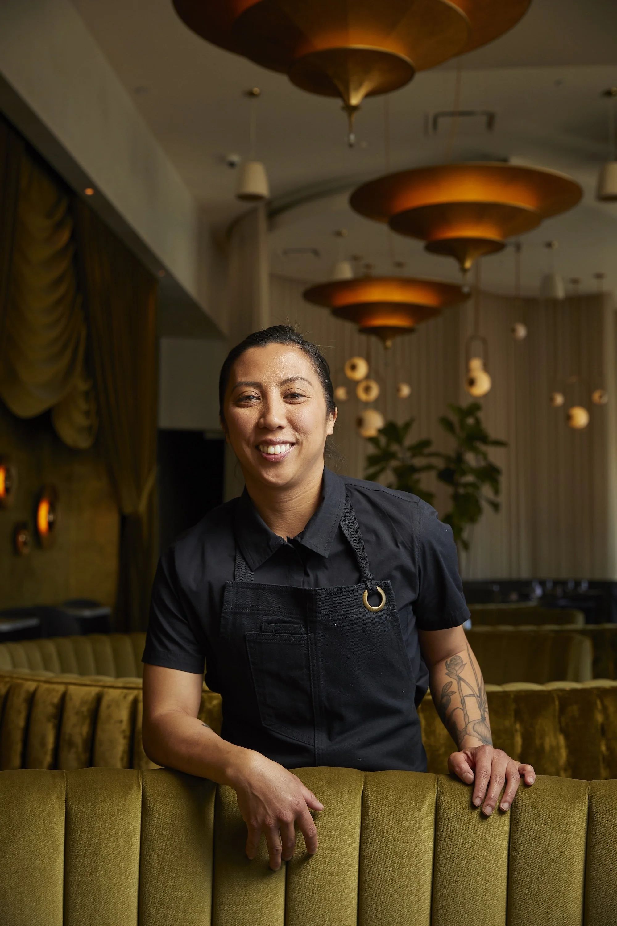 Chef Tara Monsod, Executive Chef of Animae San Diego, smiling in the dining room wearing a black apron