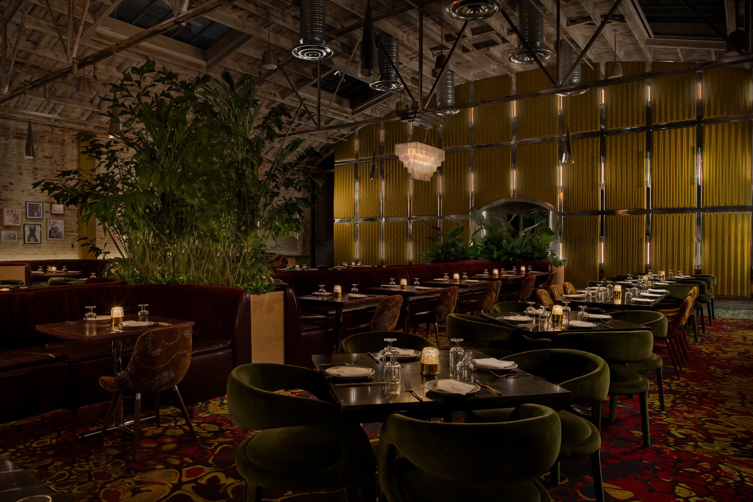 Le Coq dining room in La Jolla San Diego, featuring green velvet seating, chandelier lighting, and lush tropical plants — available for private events
