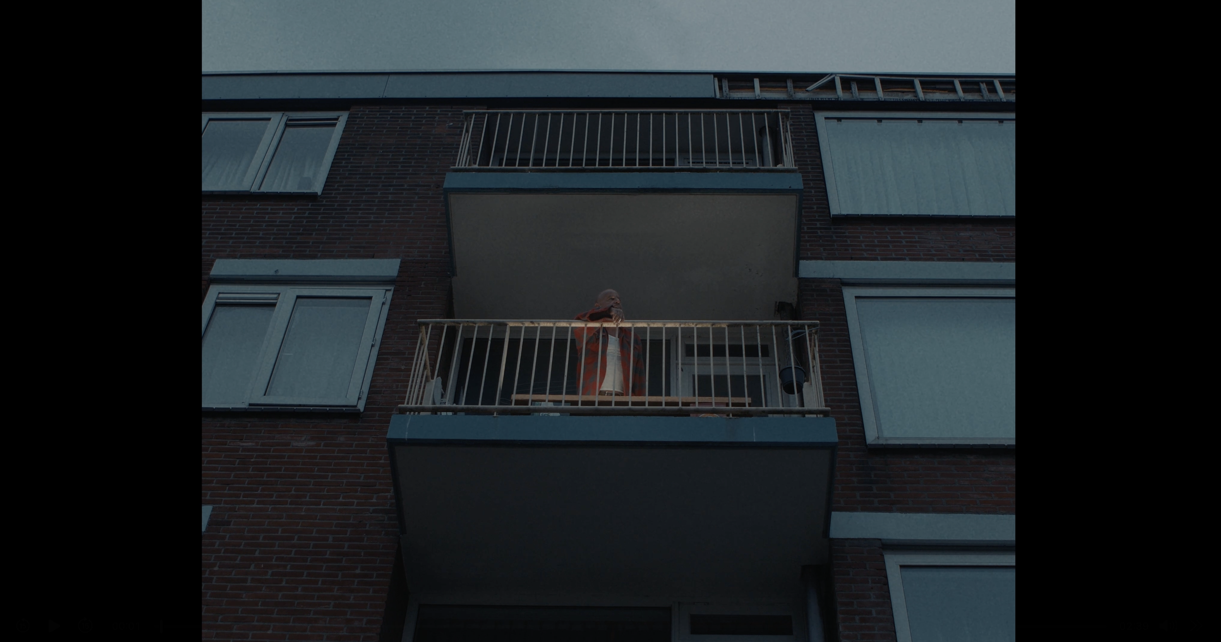 Man kijkt vanaf een balkon omhoog op een appartementengebouw met meerdere verdiepingen.