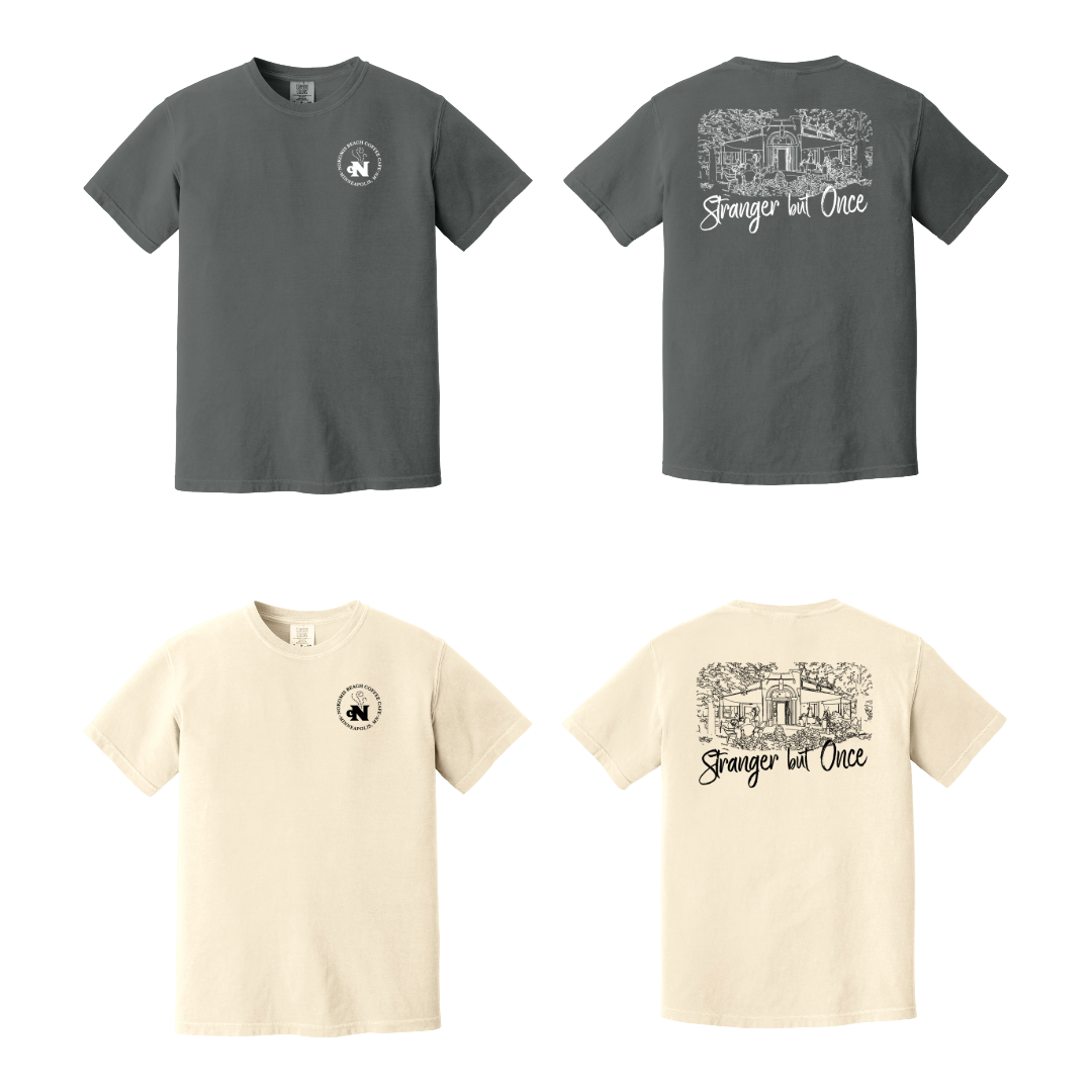 Two t-shirts in dark gray and two in cream, each with the same design. The front of each t-shirt features a small circular logo with text and a symbol. The back of each t-shirt has a line drawing of a house or building with trees and the phrase "Stranger but Once" written underneath.