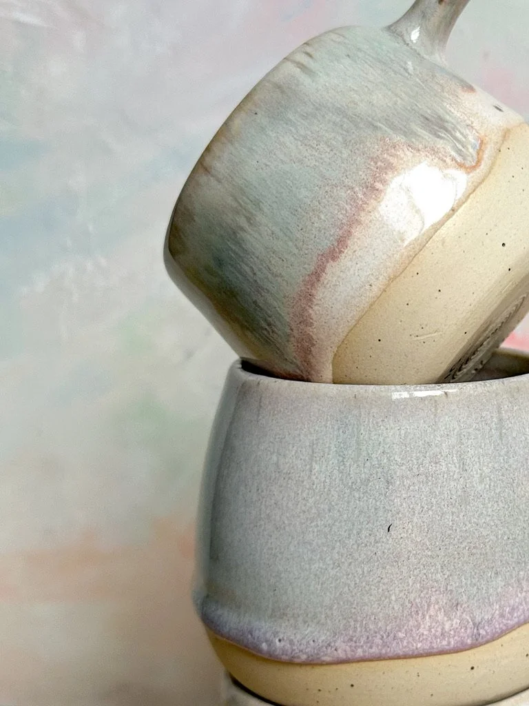Close-up of three stacked ceramic cups with a glazed finish in neutral tones.