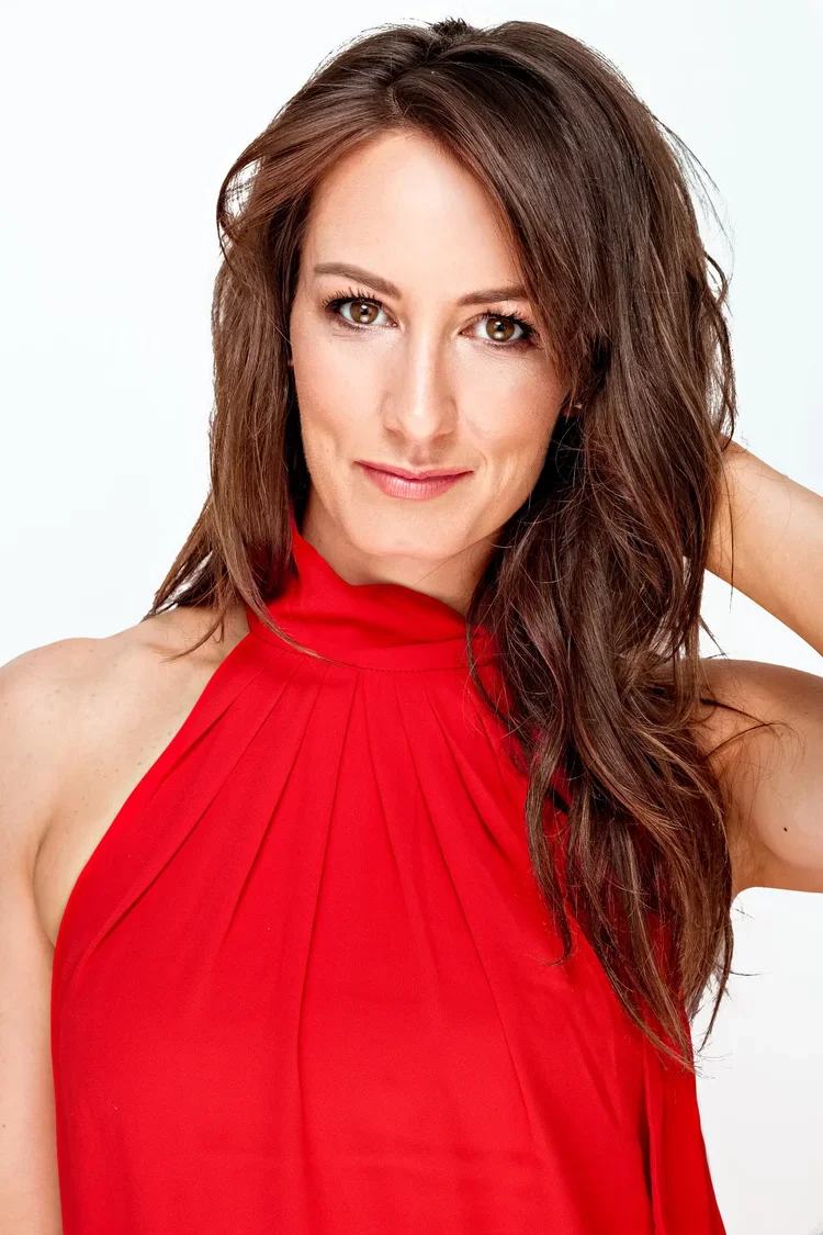 A woman with brown hair wearing a red sleeveless top against a white background.