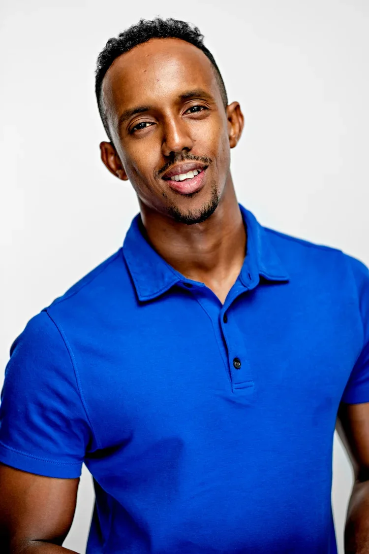 A man with short curly hair and a goatee wearing a bright blue polo shirt, looking at the camera with a slight smile against a plain white background.