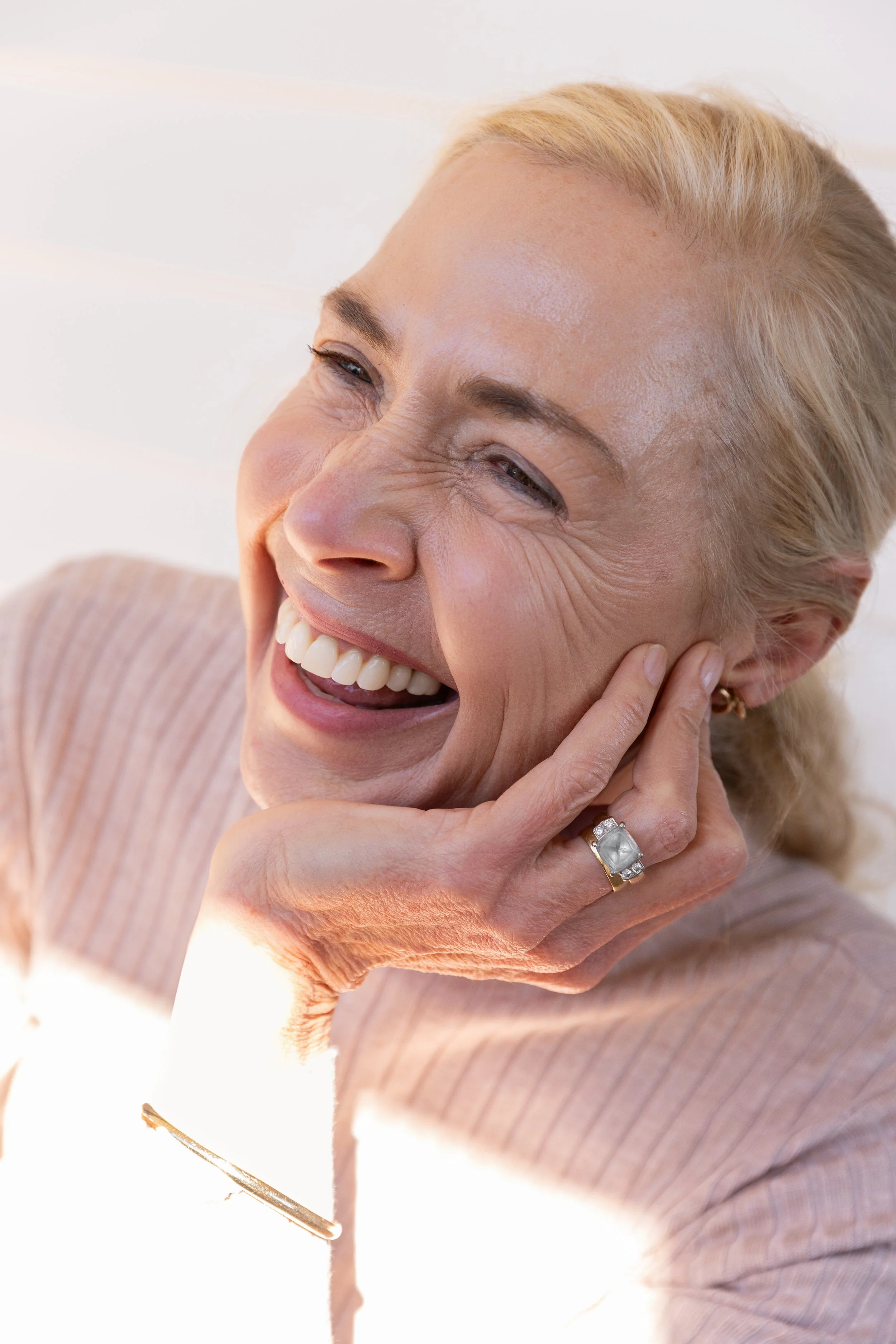 women sits in sunlight smiling