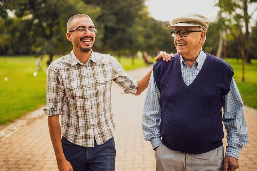 Two men walking in a park smiling and enjoying conversation.