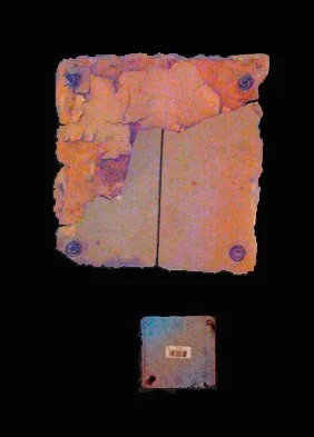 A small rectangular object with a barcode, placed below a larger, textured, rectangular piece with a rough, uneven surface and purple accents, against a black background.