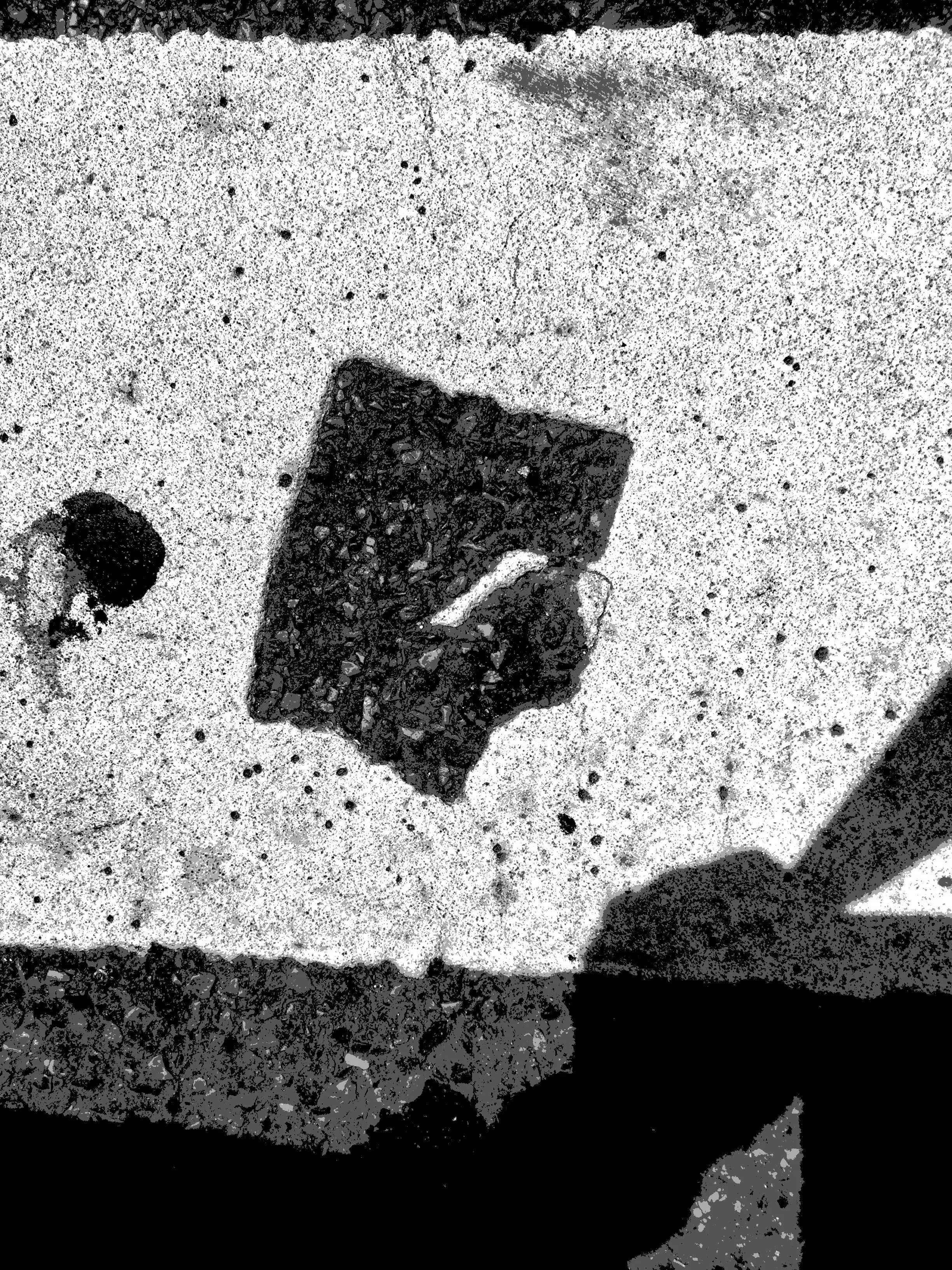 Close-up of a textured surface with a dark rectangular object embedded in the material, and other small items scattered around.
