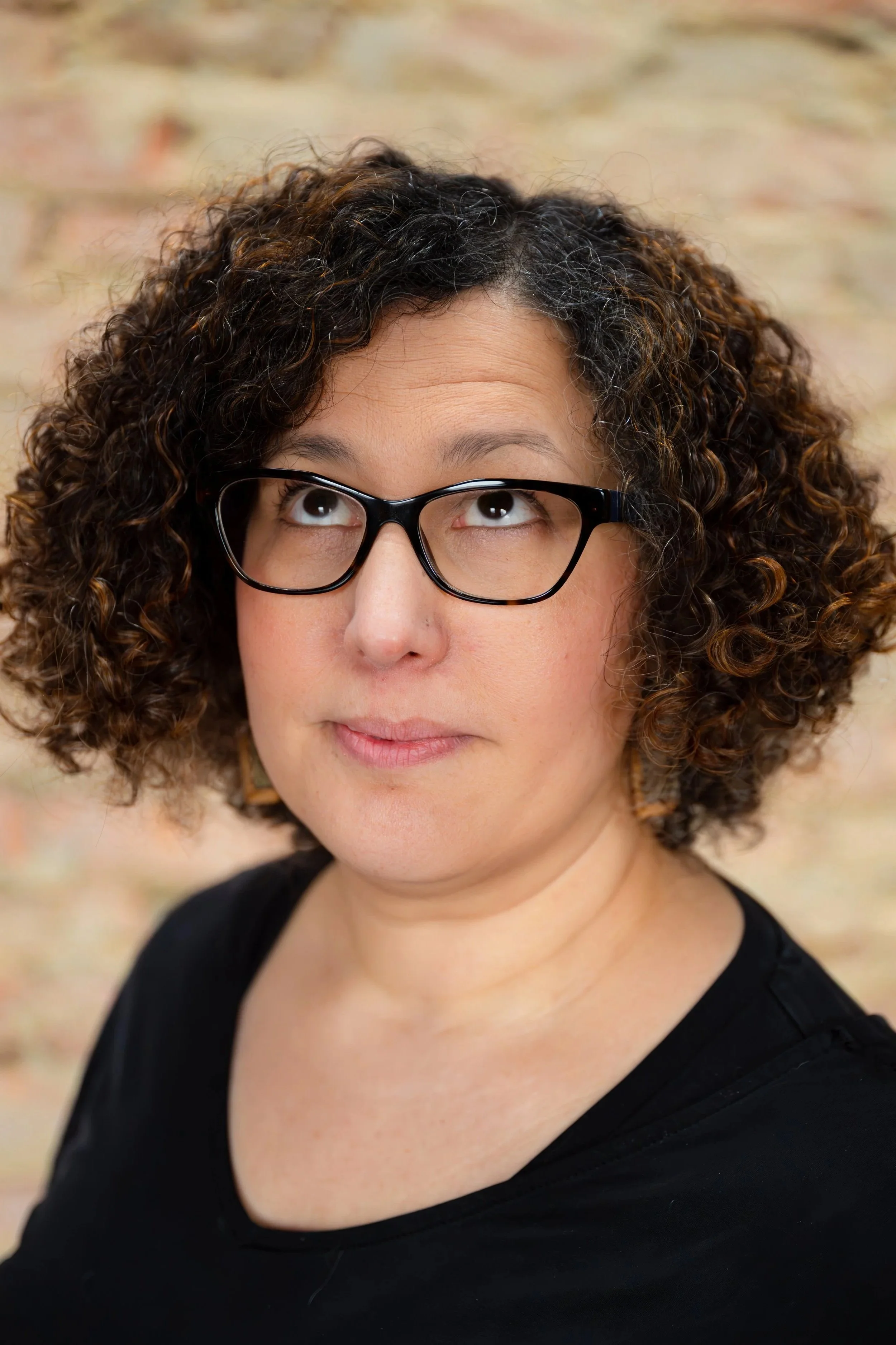 Portret van Farida voor een bakstenen muur. Ze kijkt schuin naar boven.