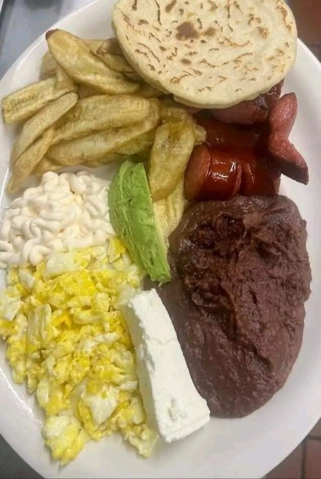 A plate of food with fries, coleslaw, lettuce, a biscuit, bacon, a piece of steak, and a slice of cheese.