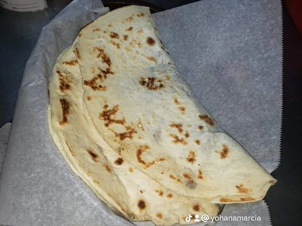 A large quesadilla with melted cheese, folded in half and toasted, on parchment paper.