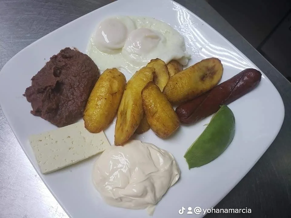 Plate with beans, fried plantains, sausage, onion, lime, cheese, and sour cream.