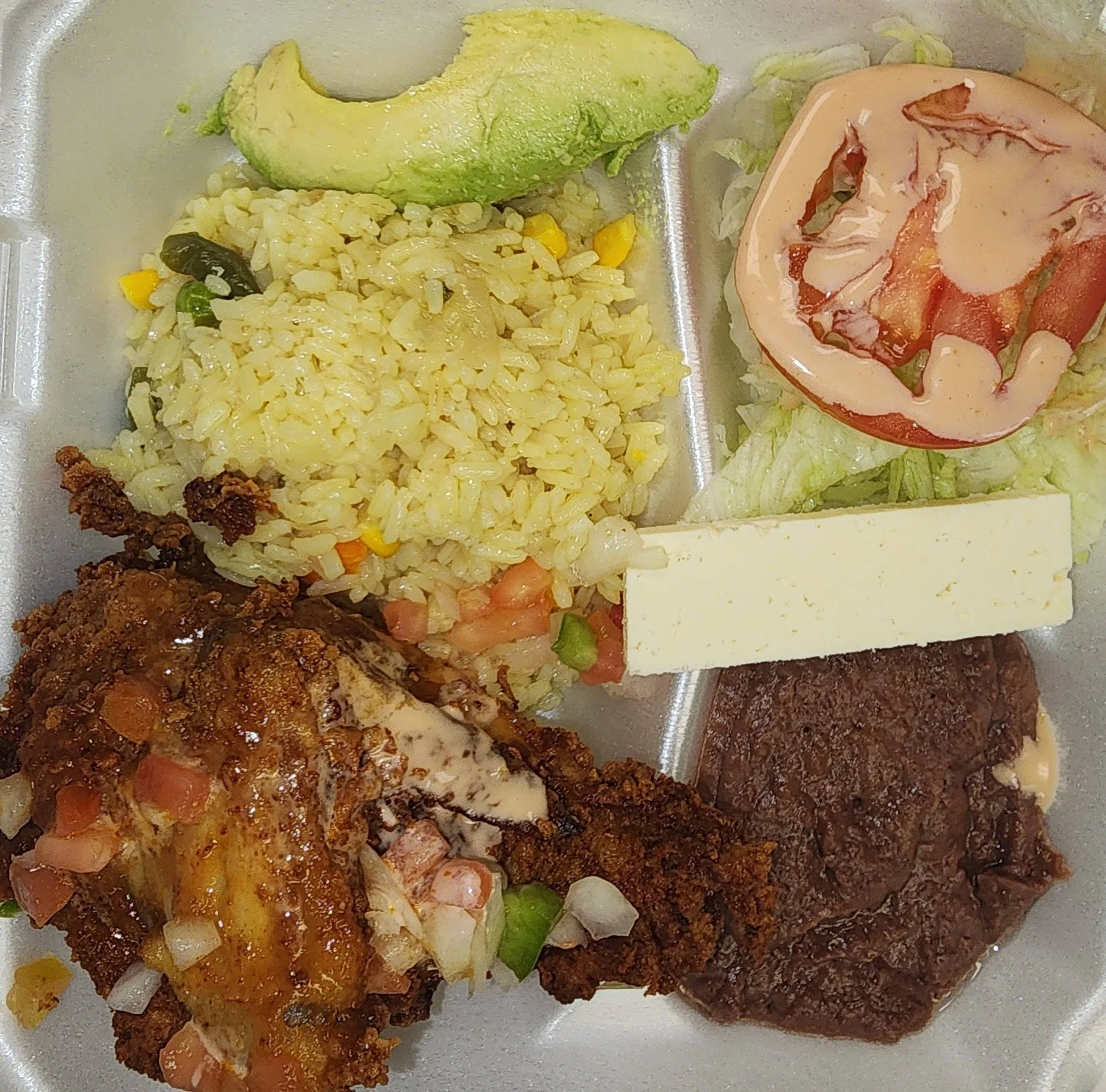 A divided tray with Mexican food including guacamole, Mexican rice with vegetables, a salad with tomato and lettuce, a piece of cheese, refried beans, and crispy beef taco with melted cheese and diced tomatoes.