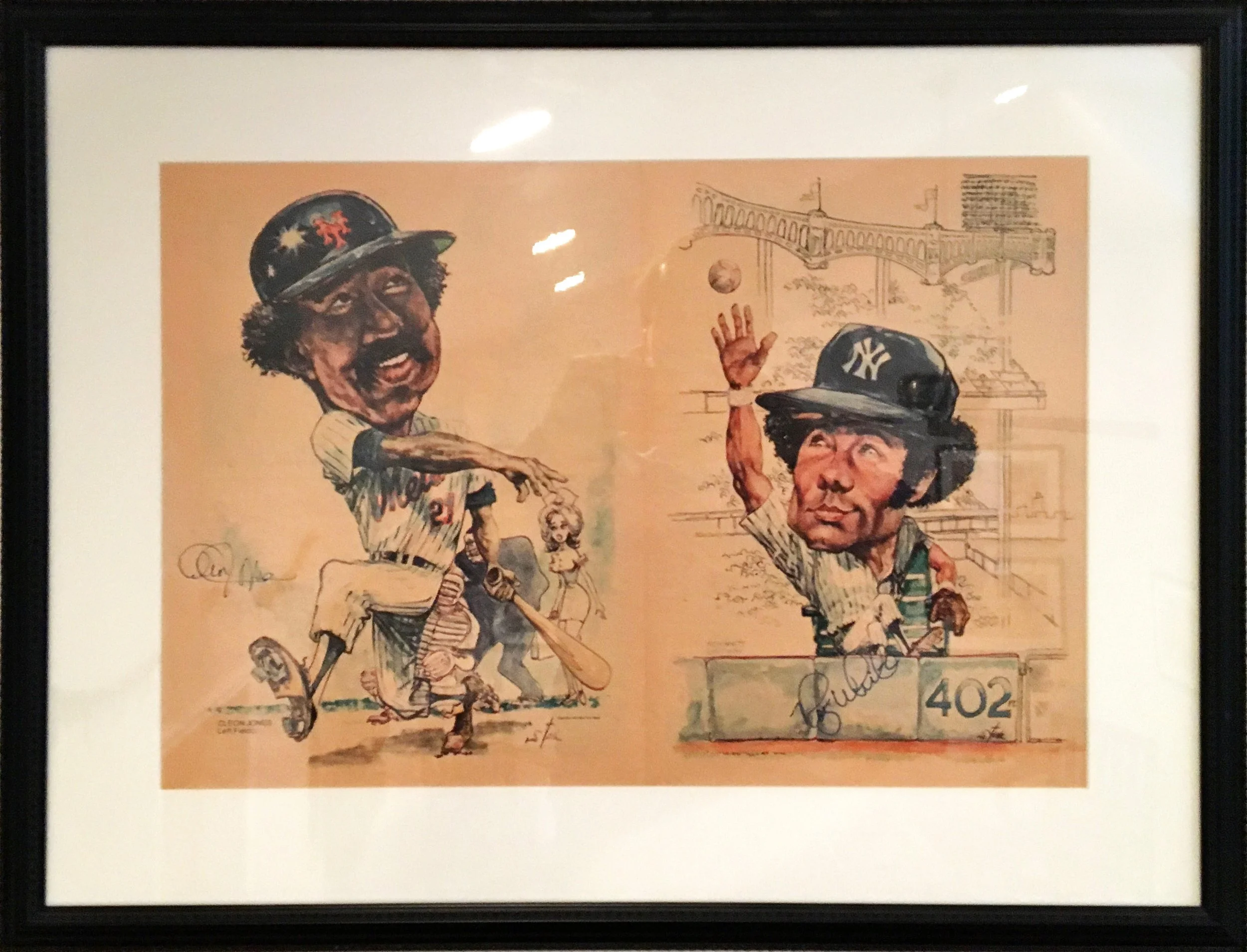 A framed caricature illustration of two baseball players, one in a New York Yankees cap and the other in a different team cap, in a baseball field scene with a bridge in the background. Signed and numbered 402.