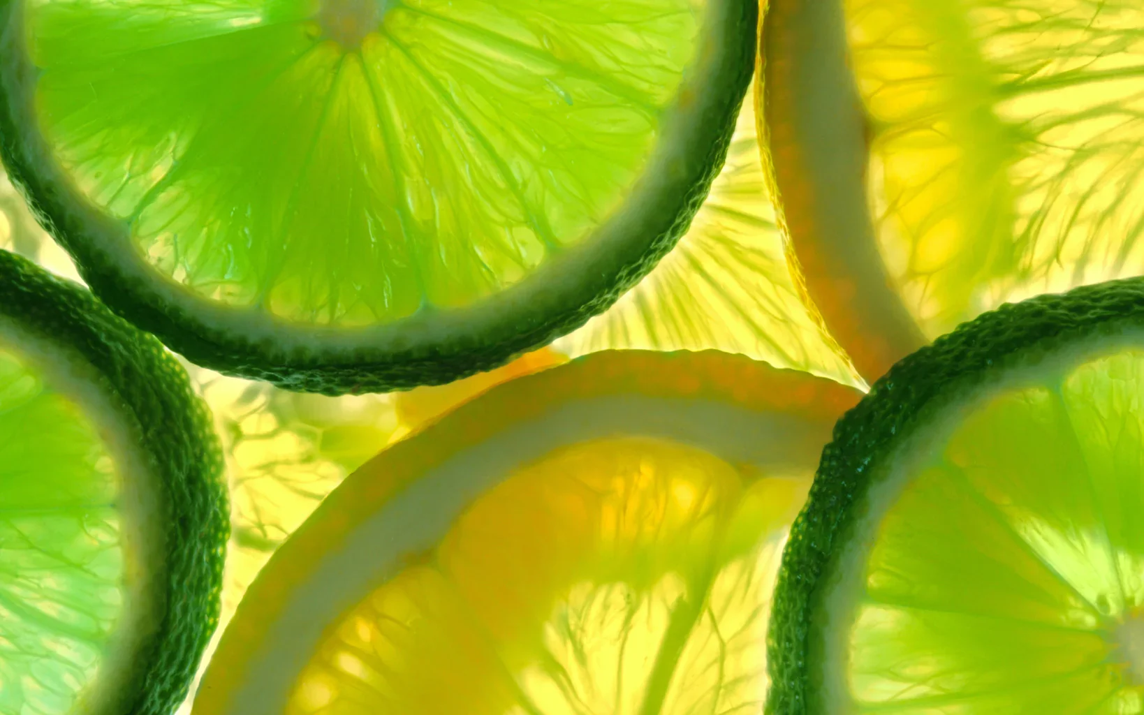 Close-up of lime slices illuminated from behind, showcasing their green rinds and translucent, juicy interior.