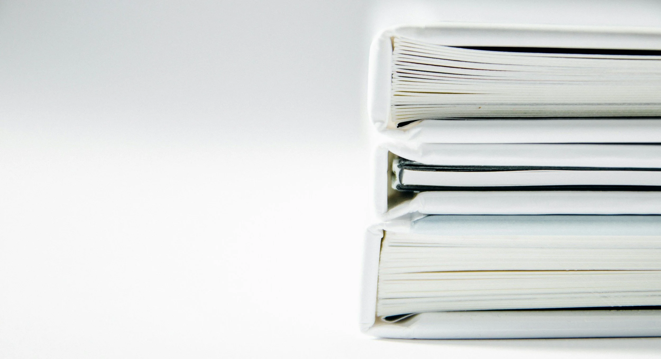Stack of white binders or folders on a plain white background.