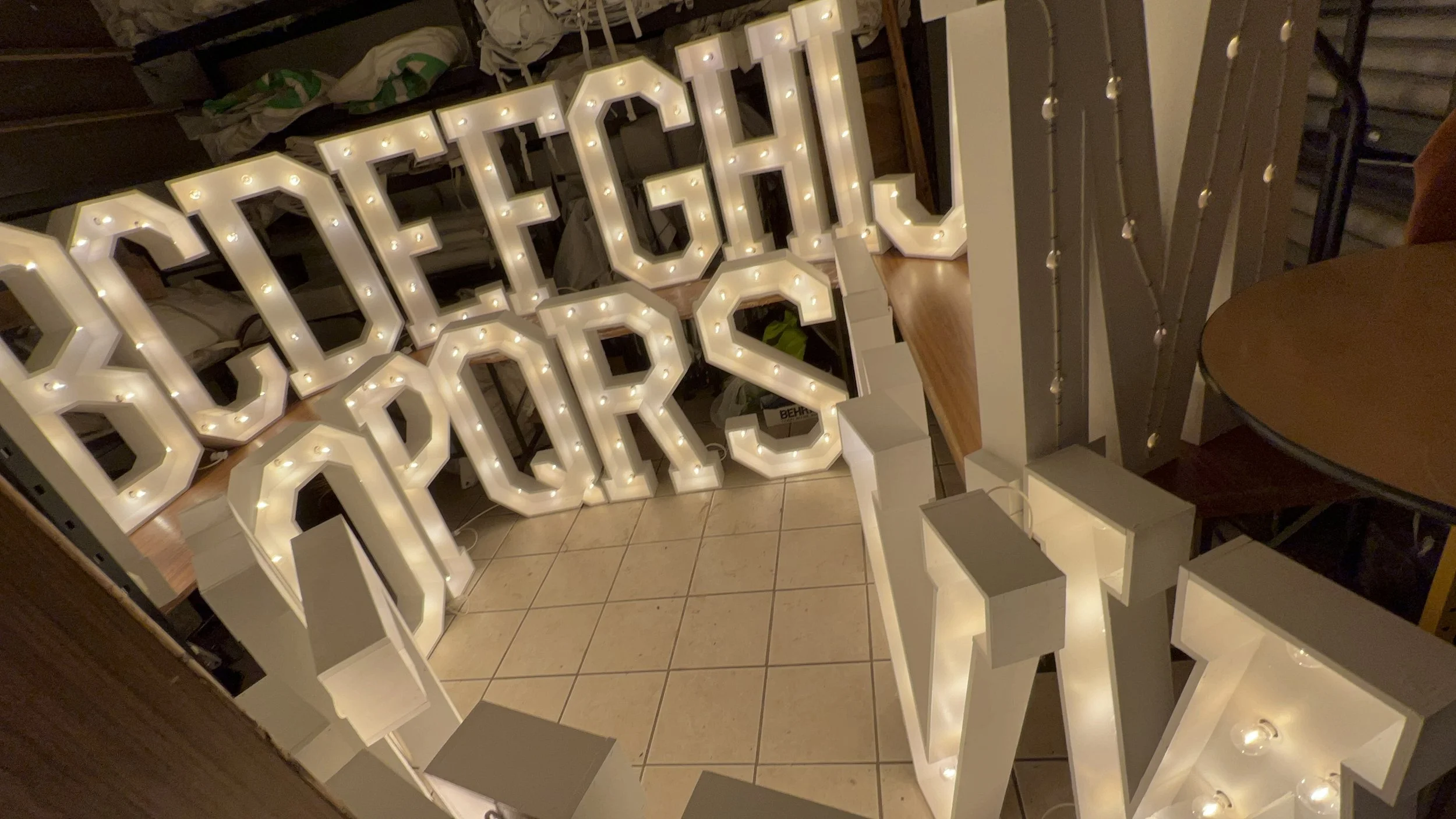 Decorative marquee lights spell out "Good Vibes" in a dimly lit setting.