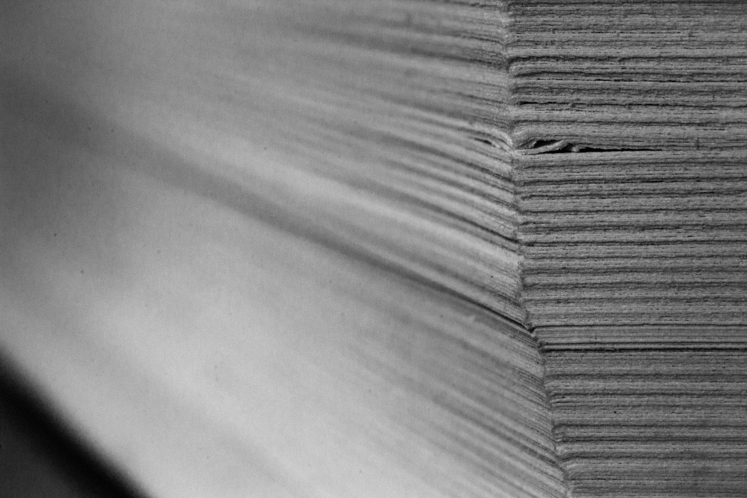 Close-up black and white photo of the edges of a stack of paperback books.
