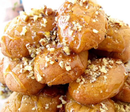 Melomakarona — Soft Greek honey spiced cookies soaked in a fragrant honey syrup and topped with crushed walnuts and cinnamon.