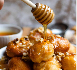 Loukoumades — Golden, bite-sized Greek dough puffs fried until crisp and drizzled with honey syrup, then sprinkled with cinnamon and walnuts.*