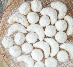 Kourambiethes — Buttery Greek shortbread cookies with a melt-in-your-mouth texture, coated in powdered sugar.
