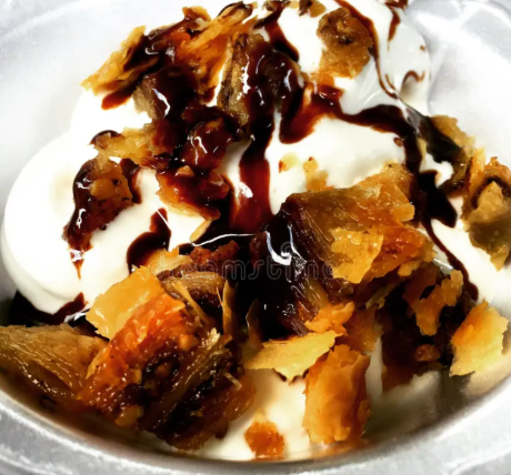 Baklava Sundae - Creamy vanilla ice cream topped with baklava, drizzled with chocolate syrup, and finished with whipped cream and a cherry.*