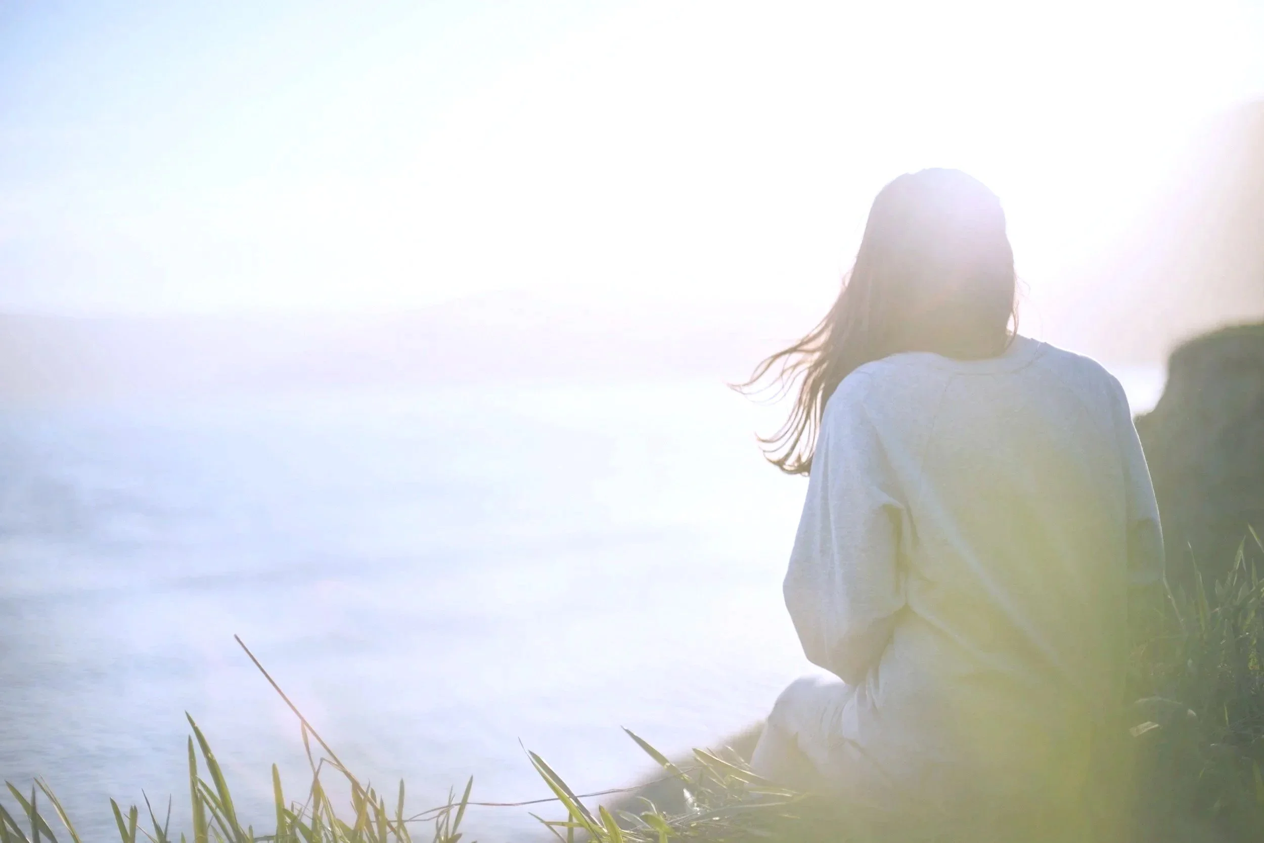 Woman sitting by the ocean looking at the water