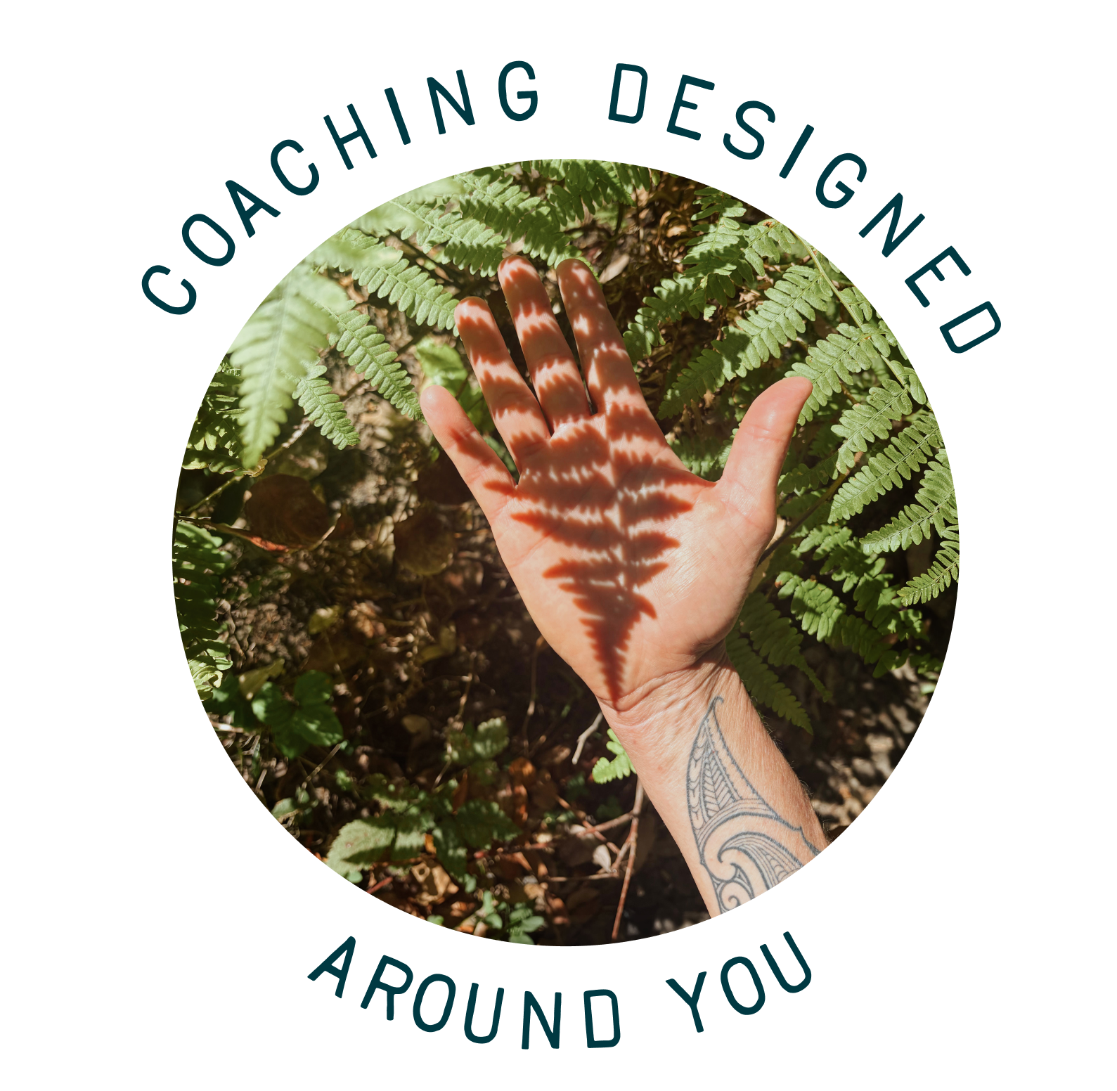 A hand with a tattoo is placed against green fern leaves, with shadows of the leaves creating patterns on the hand, in a natural outdoor setting.