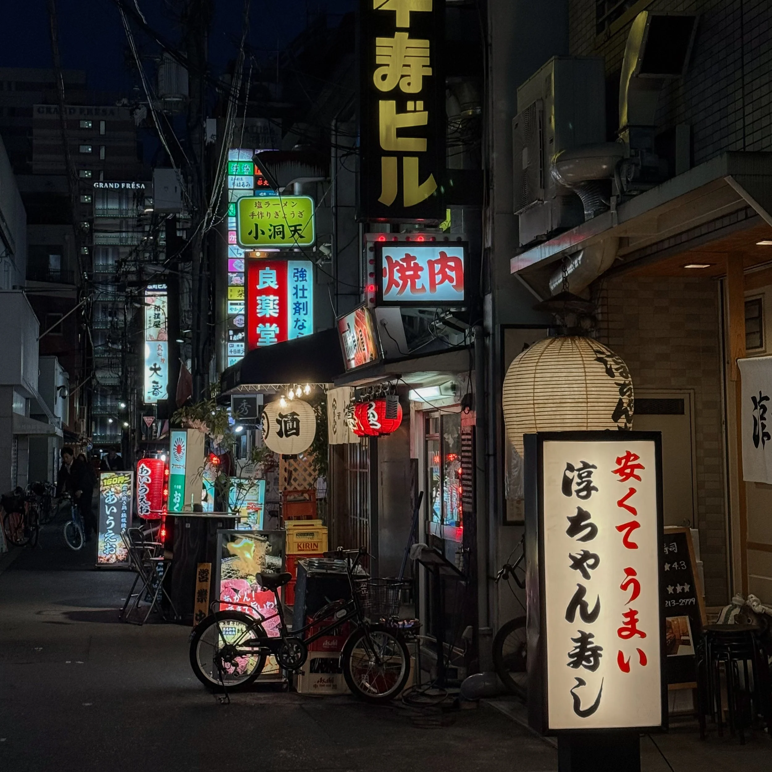 A vibrant street scene at night in a Japanese city with glowing neon signs and a traditional lantern, representing immersive travel packages