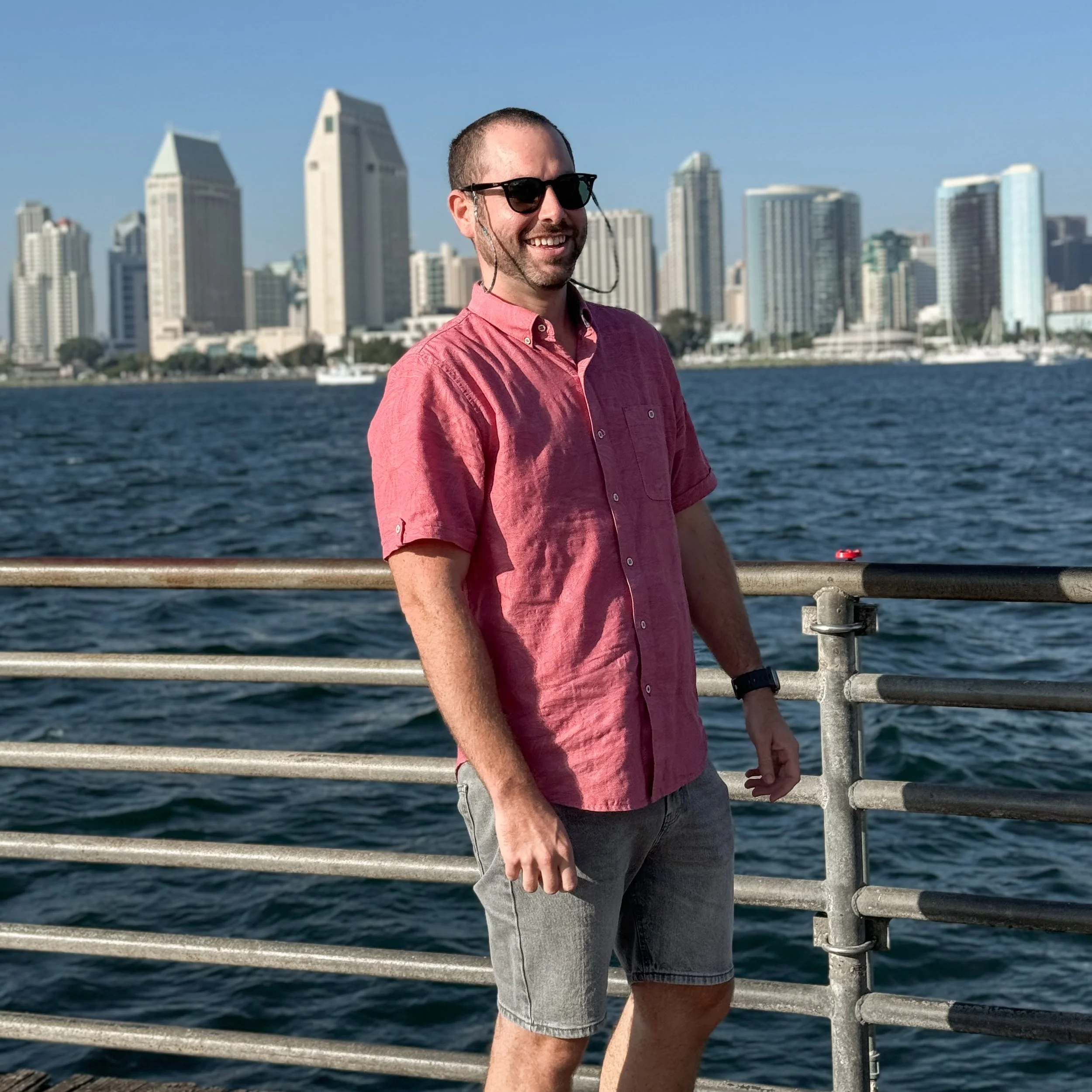 David, founder of Velora Travel Studio, smiling in front of a city skyline and waterfront, offering boutique luxury travel planning services.