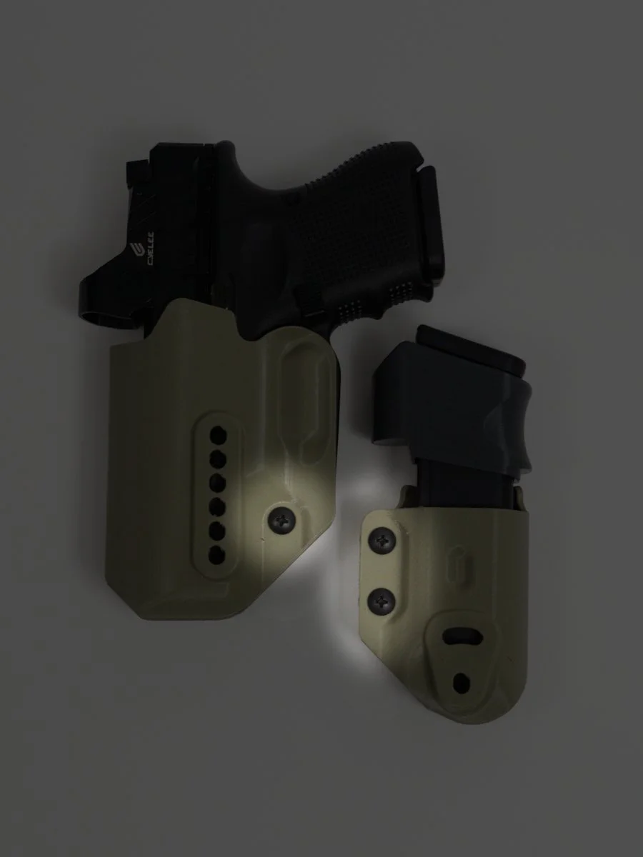 A black Glock handgun and magazine, both in foliage green Mockingbird Holsters, on a white surface, with spotlights on the retention adjustment screws