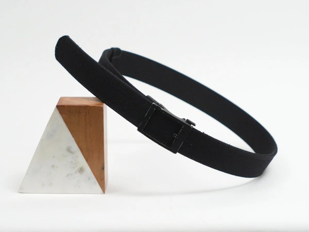 Black belt resting against a triangular marble and wood block against a white background.