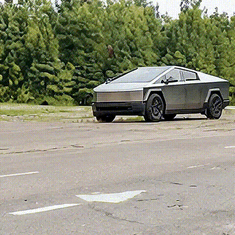 A Tesla Cybertruck parked in an empty lot with trees in the background.